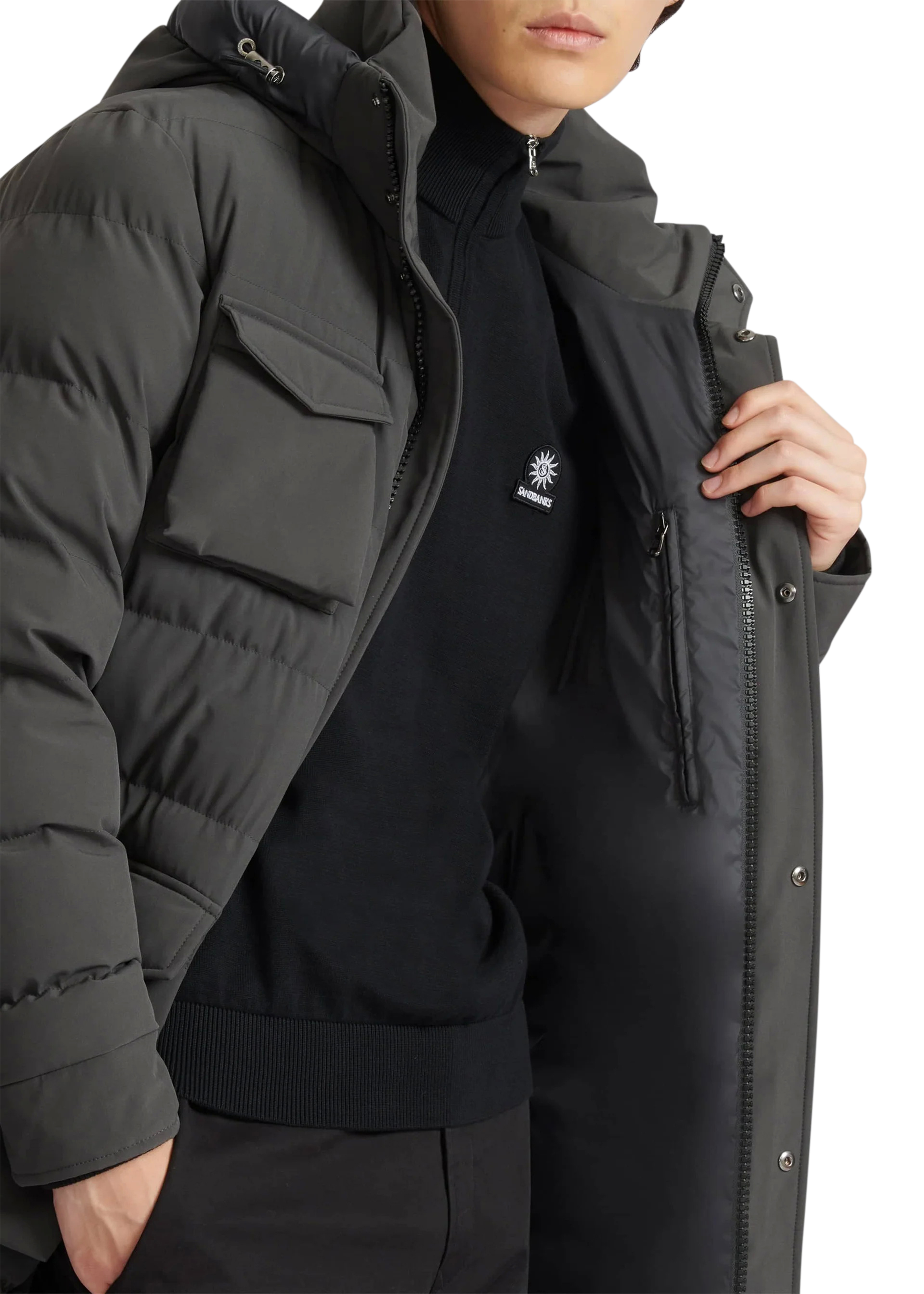 Person wearing a black puffer jacket over a black hoodie with a logo.