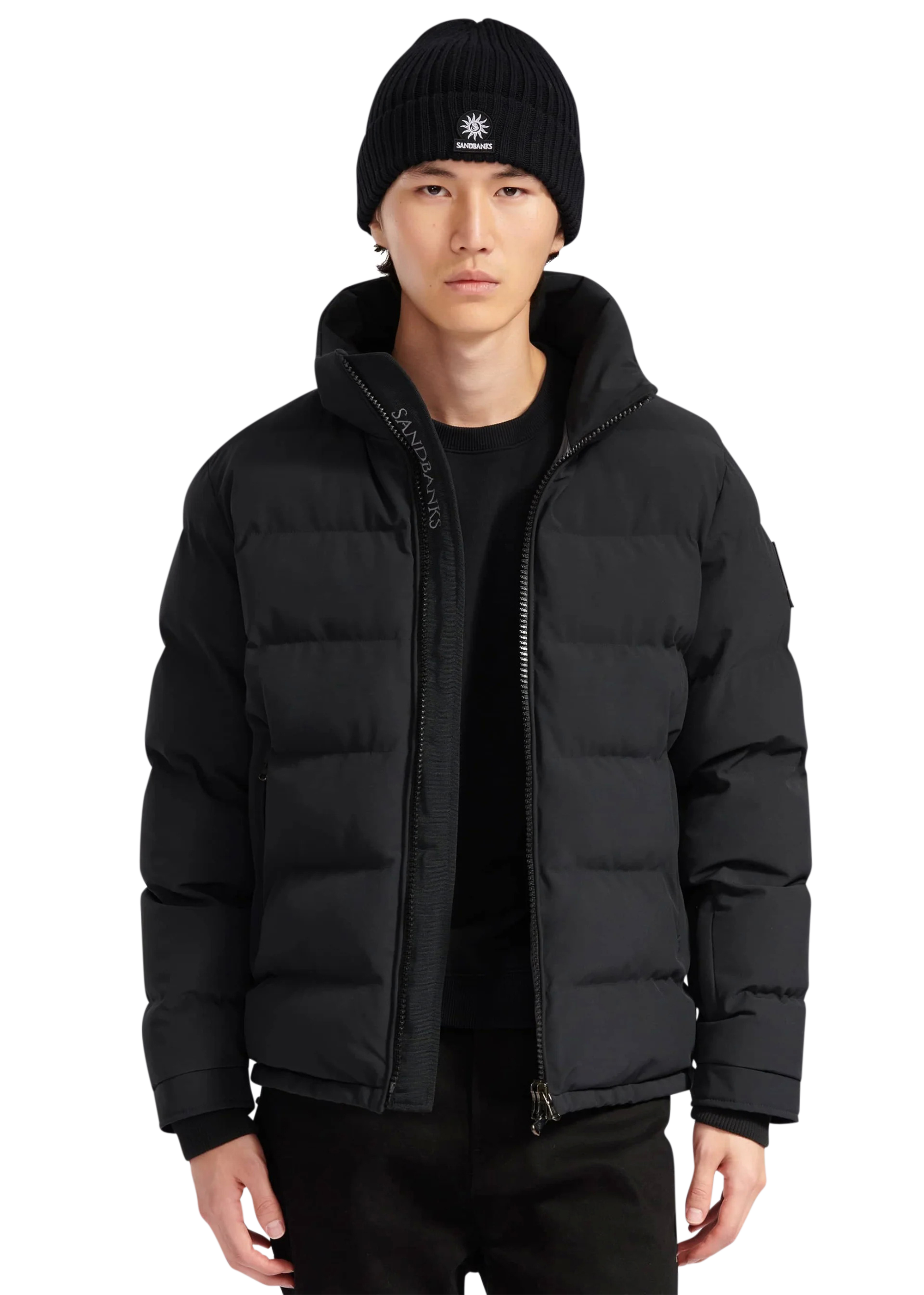 Person wearing a black puffer jacket and beanie on a white background