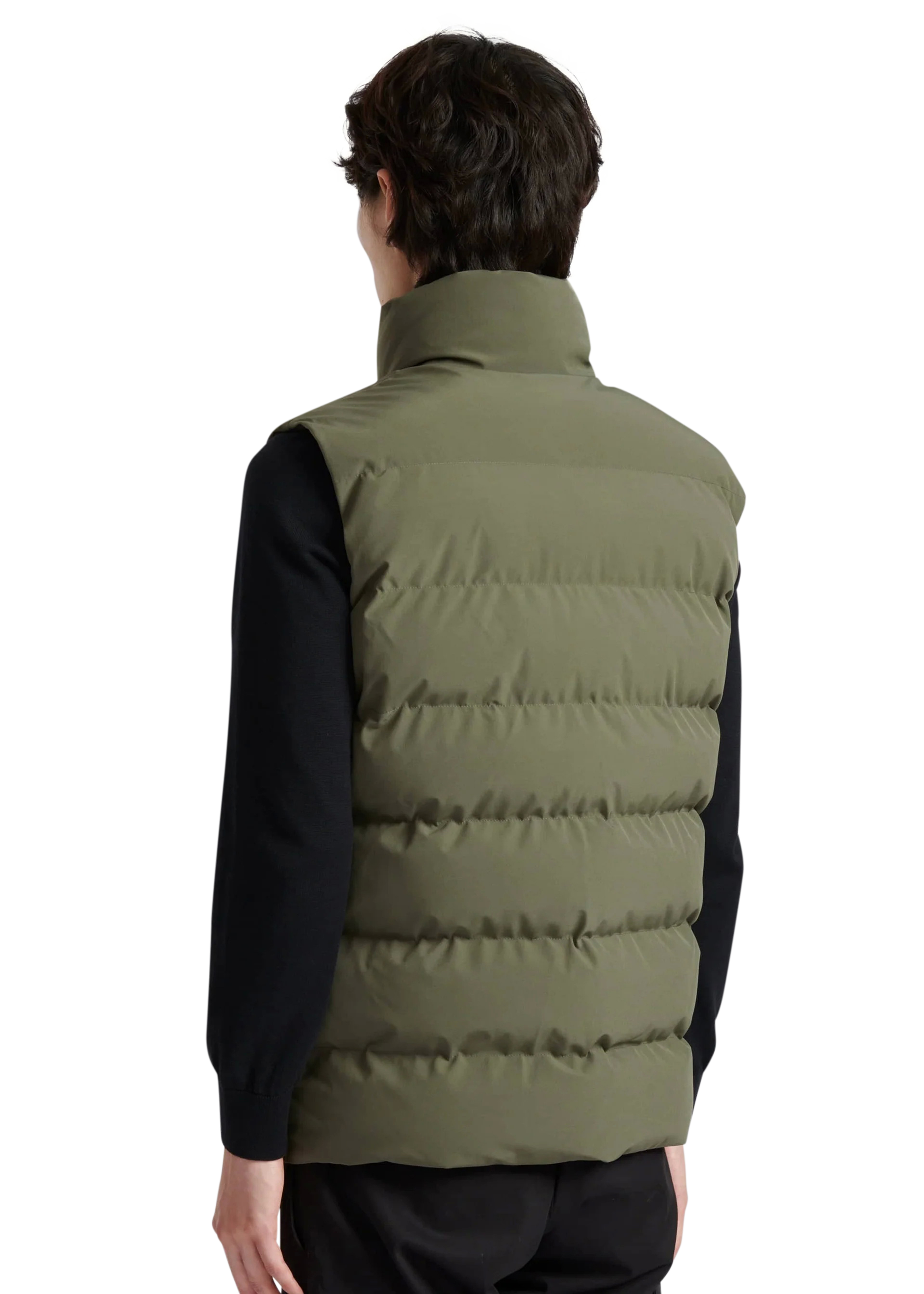 Person wearing a green puffer vest over a black shirt on a white background