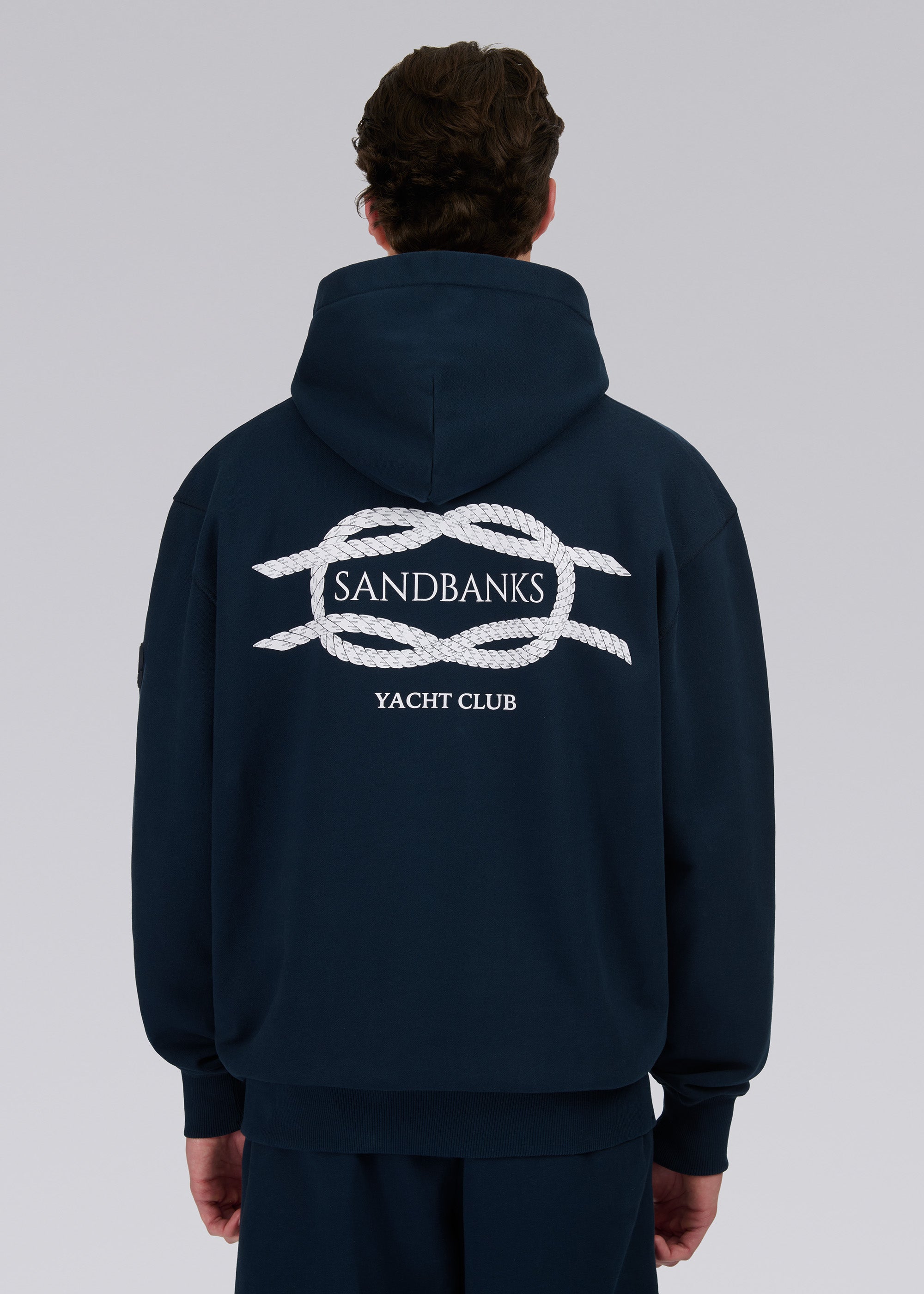 Model wearing a navy hoodie with a logo on a gray background