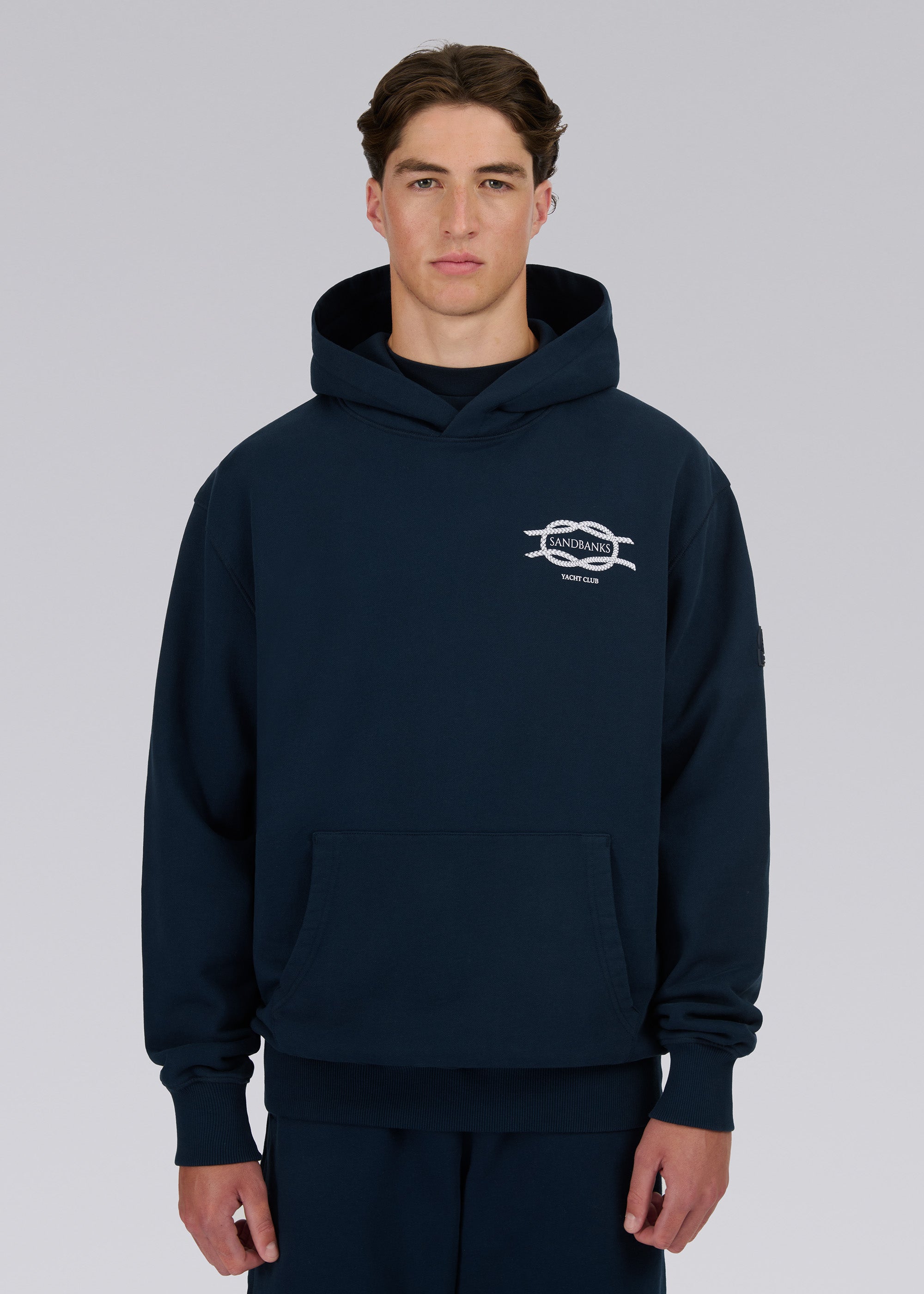 Model wearing a navy hoodie with a logo on a gray background