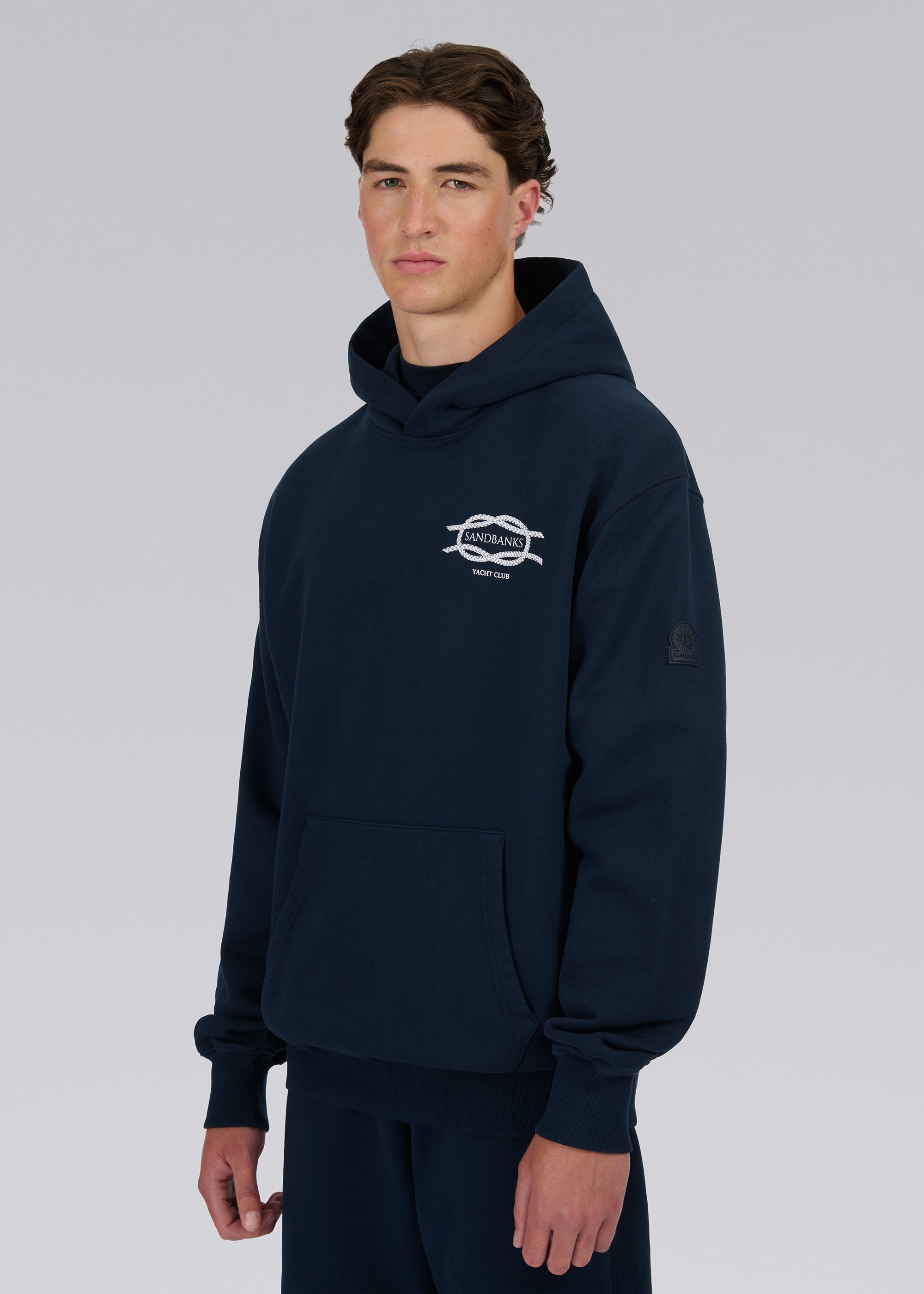 Model wearing a navy hoodie with a logo on a gray background