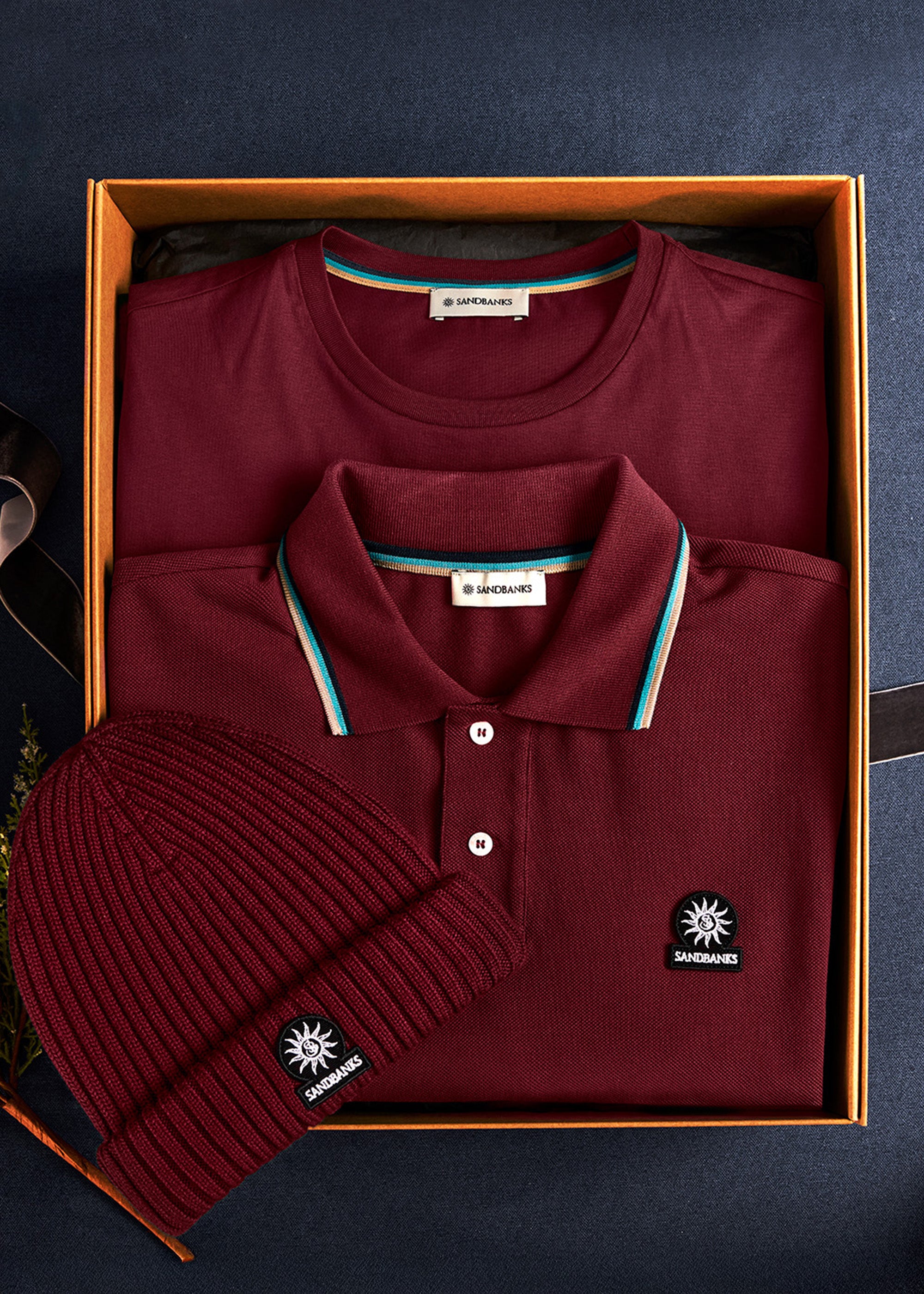 port polo shirt, beanie, and box with brand label on a dark background