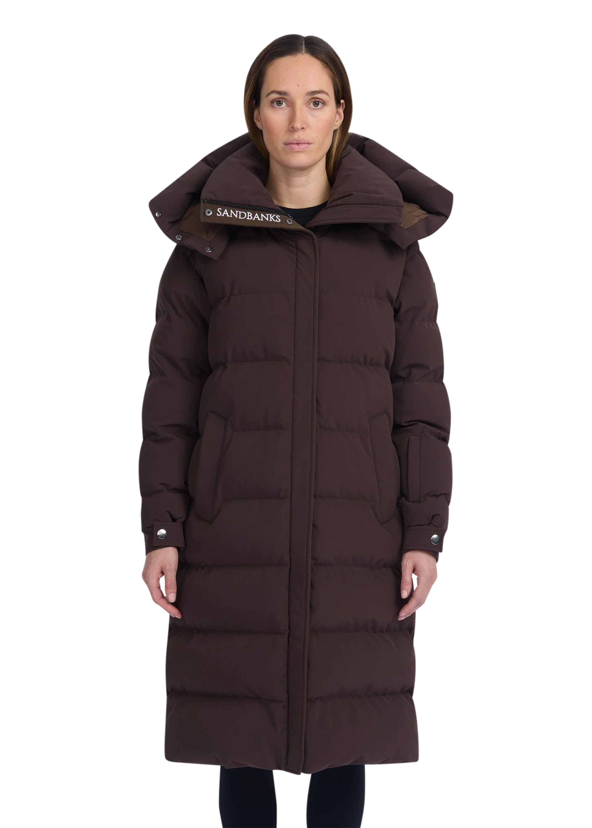 Woman wearing a long brown puffer coat with a hood on a white background