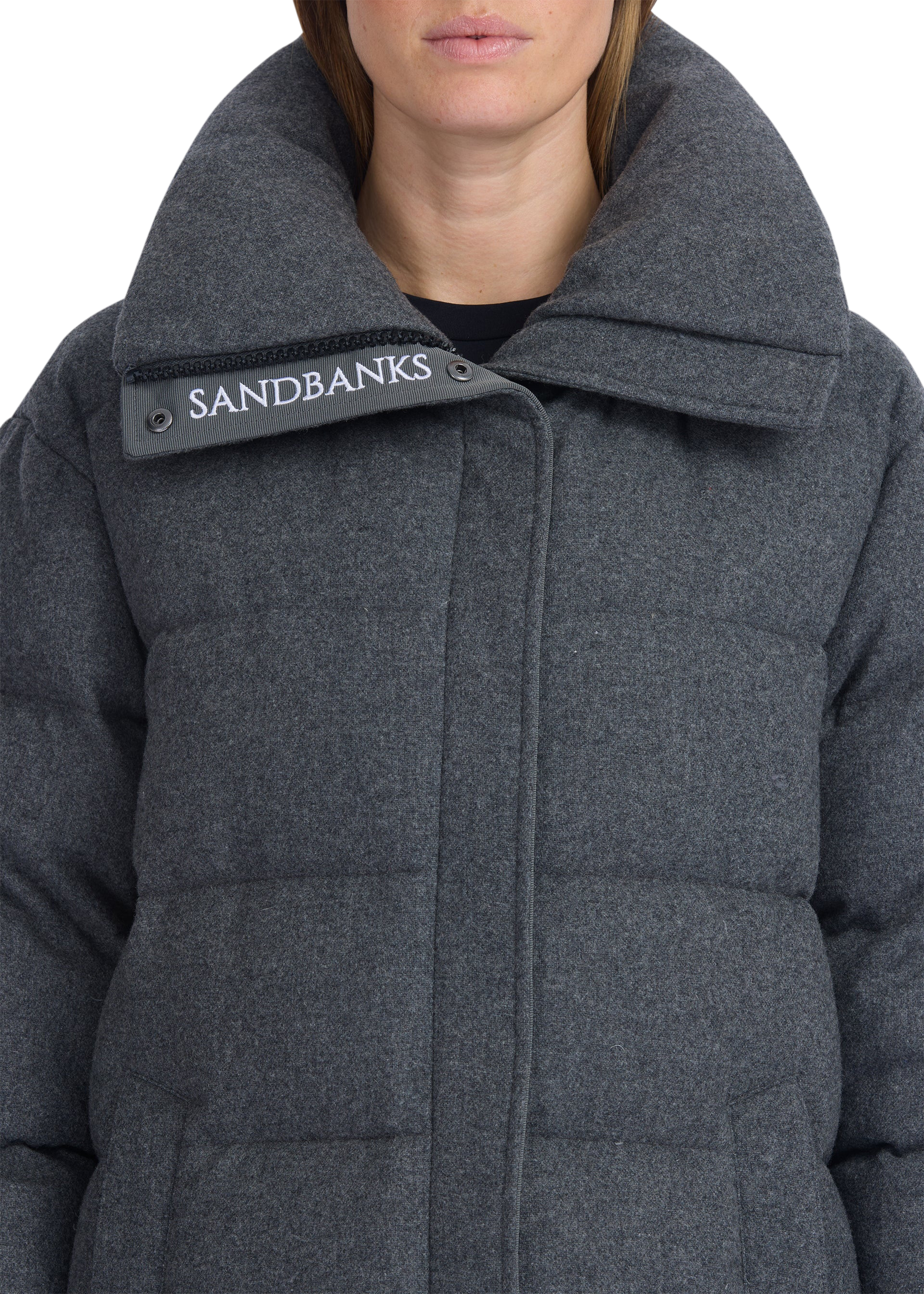 Close-up of a person wearing a gray Sandbanks coat with a visible brand logo.