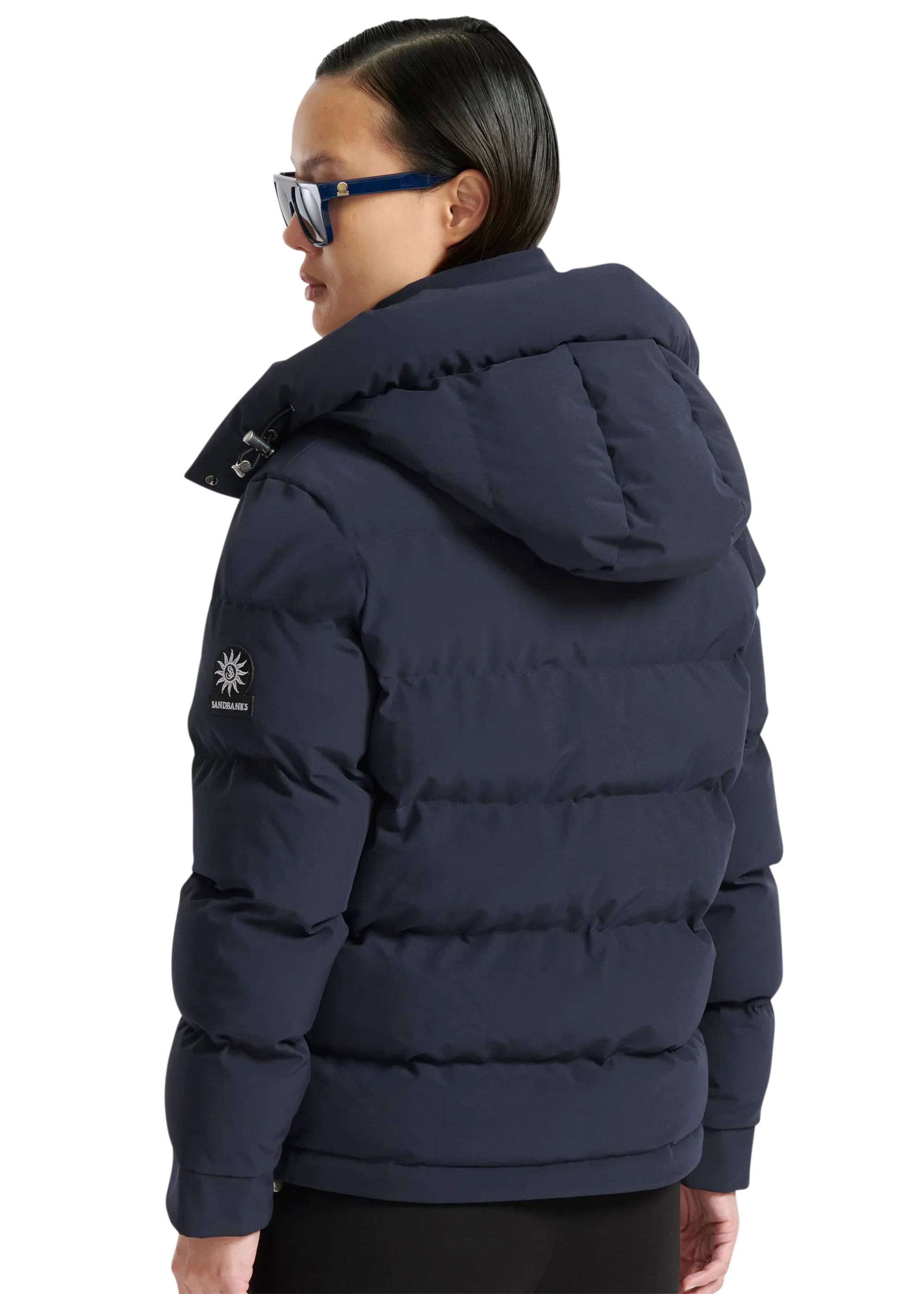 Person wearing a navy blue puffer jacket with a brand logo on a white background