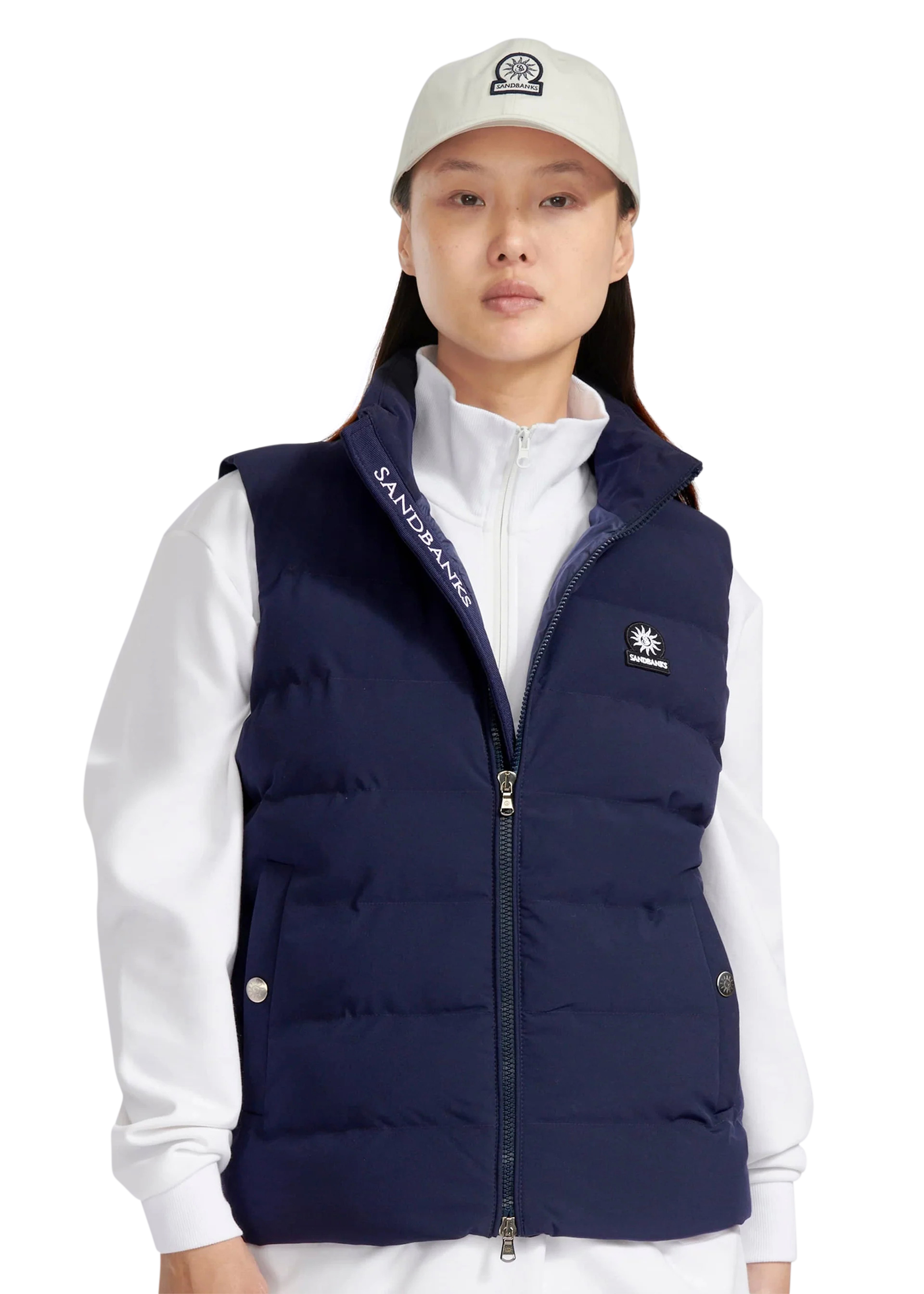 Person wearing a navy puffer vest over a white shirt with a visible brand logo.
