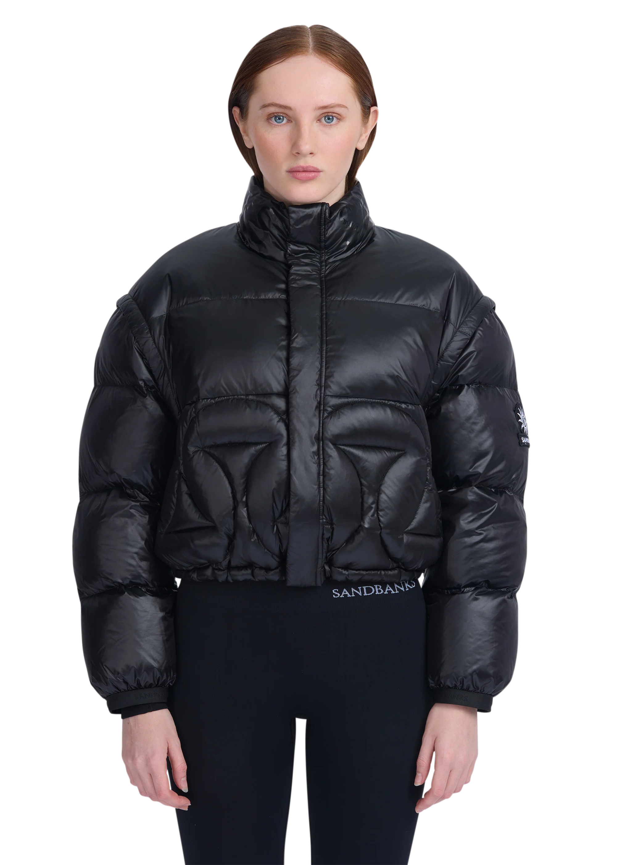 Person wearing a black puffer jacket with 'Sandbanks' branding on a white background