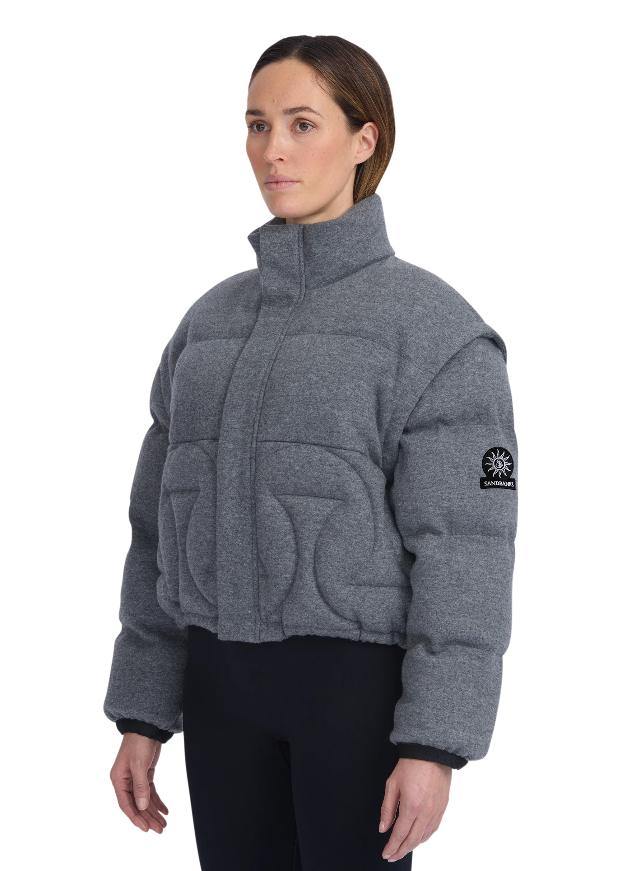 Woman wearing a gray quilted jacket with a brand logo on a white background