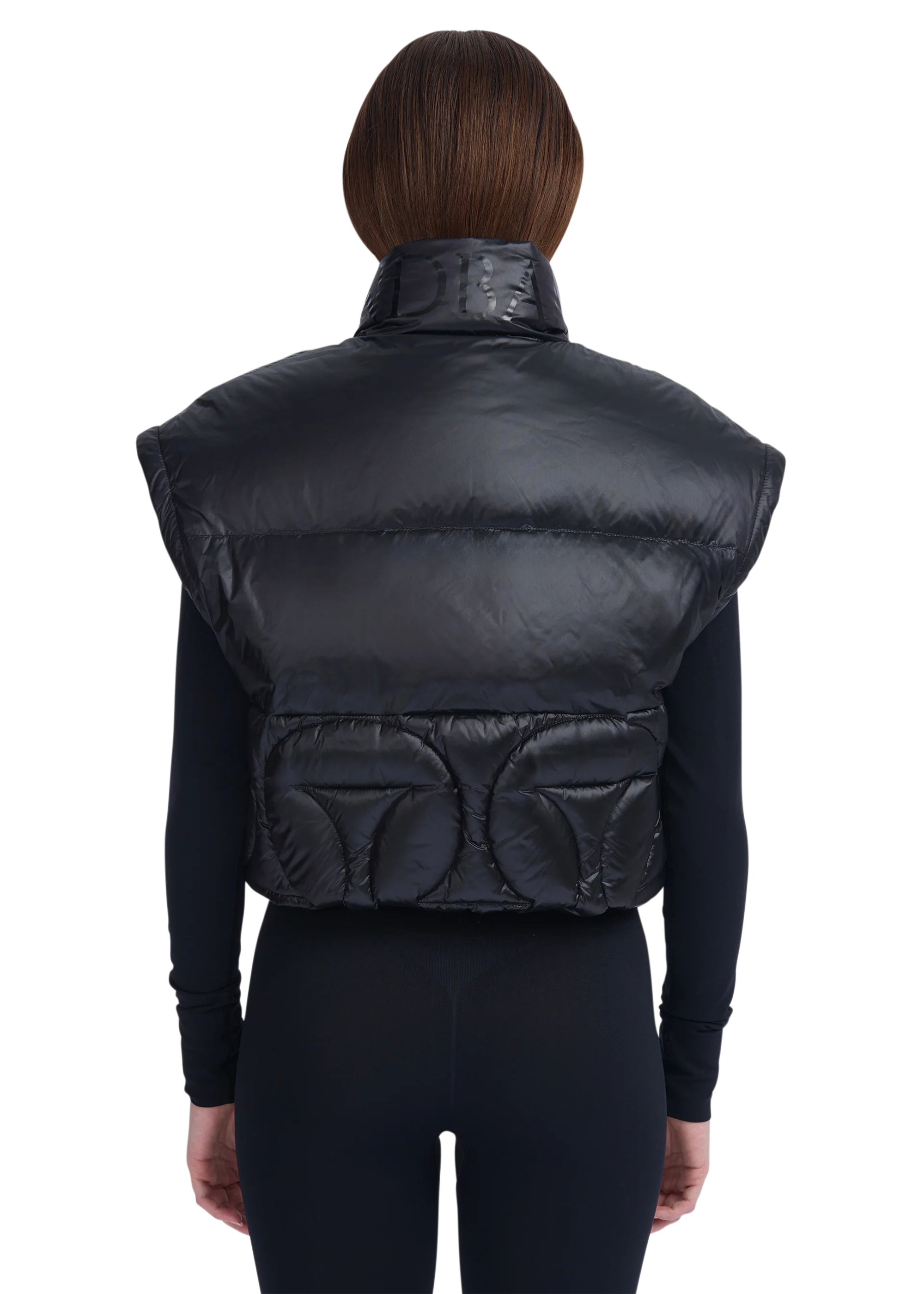 Black puffer vest worn by a person on a white background