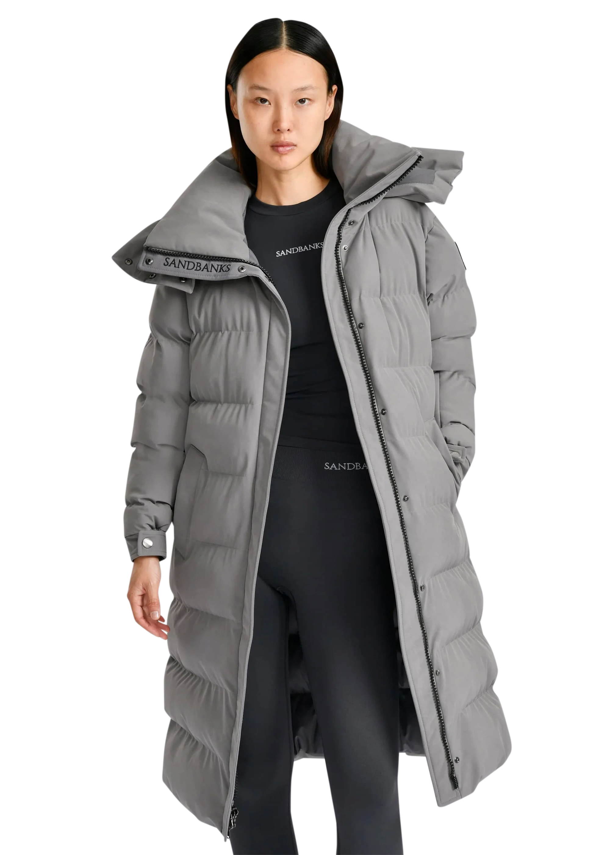 Person wearing a long gray puffer coat with a hood on a white background