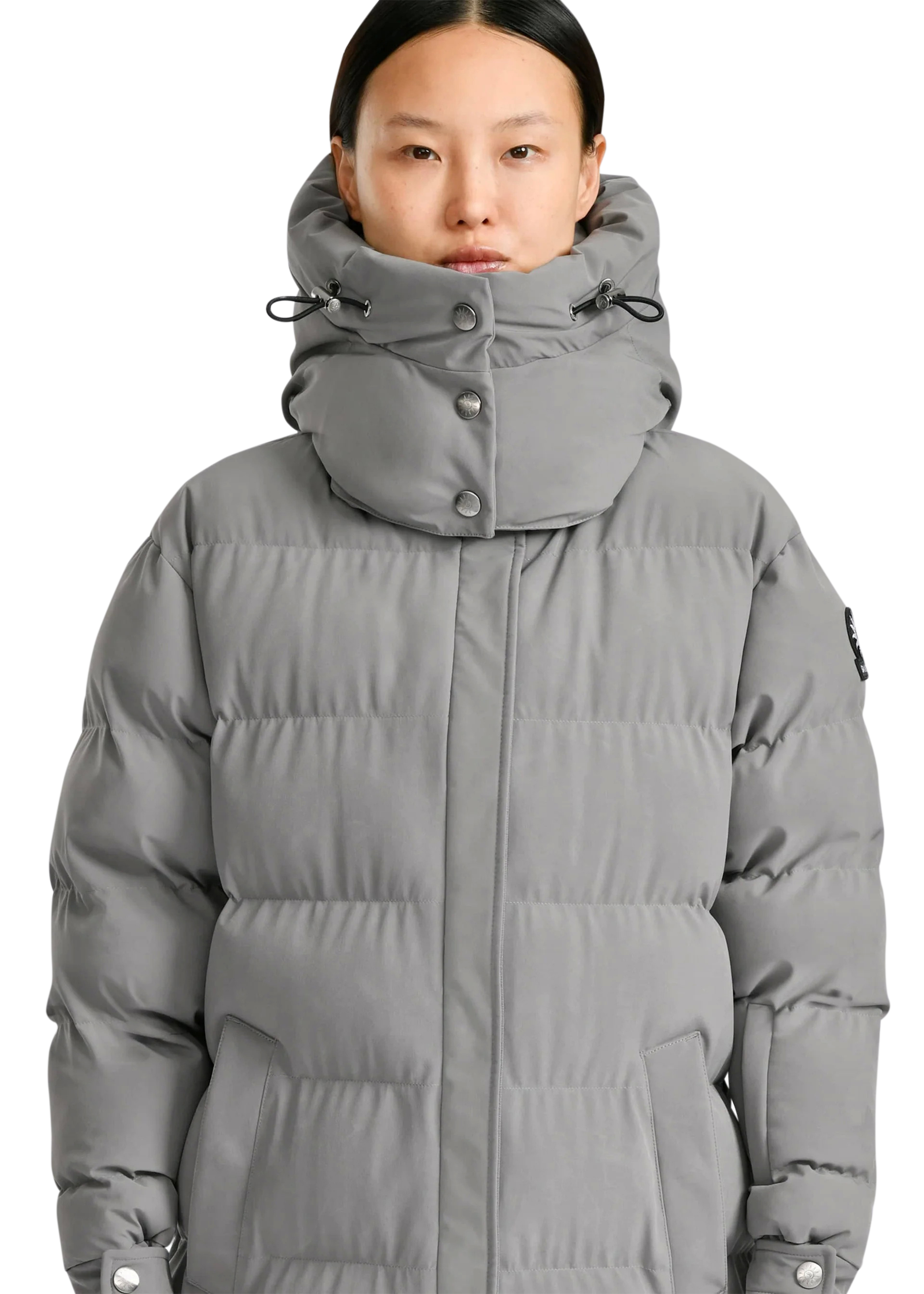 Person wearing a gray puffer jacket on a white background