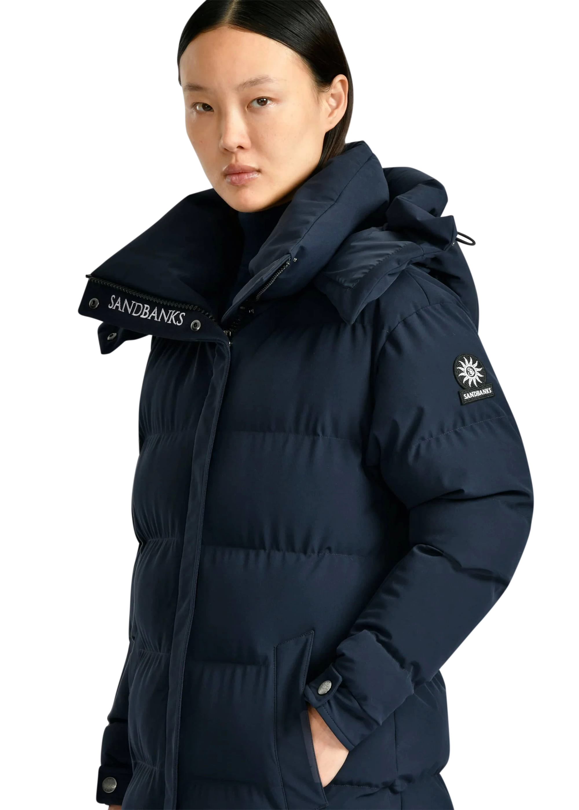 Person wearing a navy blue puffer jacket with brand logos on a white background