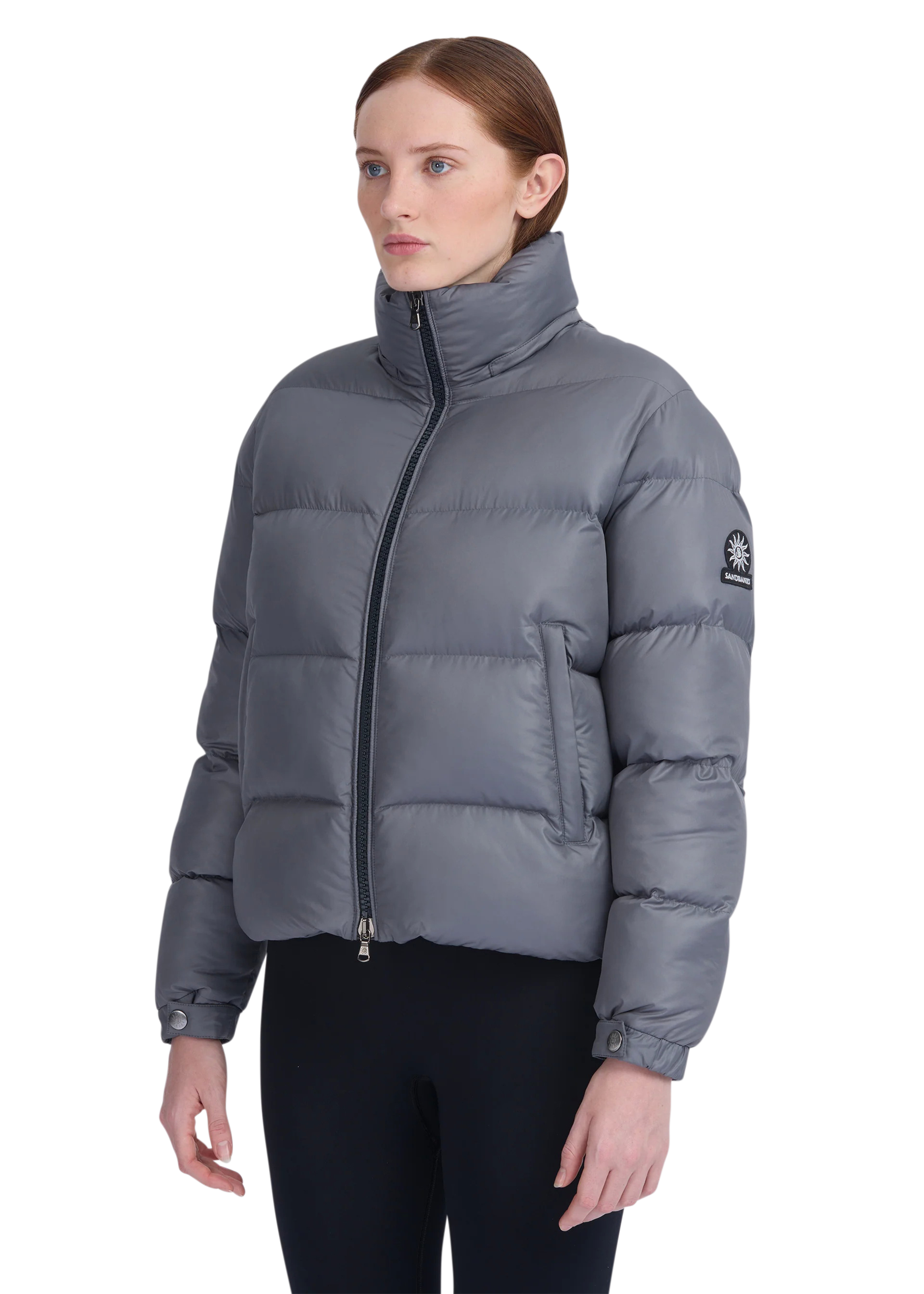 Woman wearing a gray puffer jacket on a white background