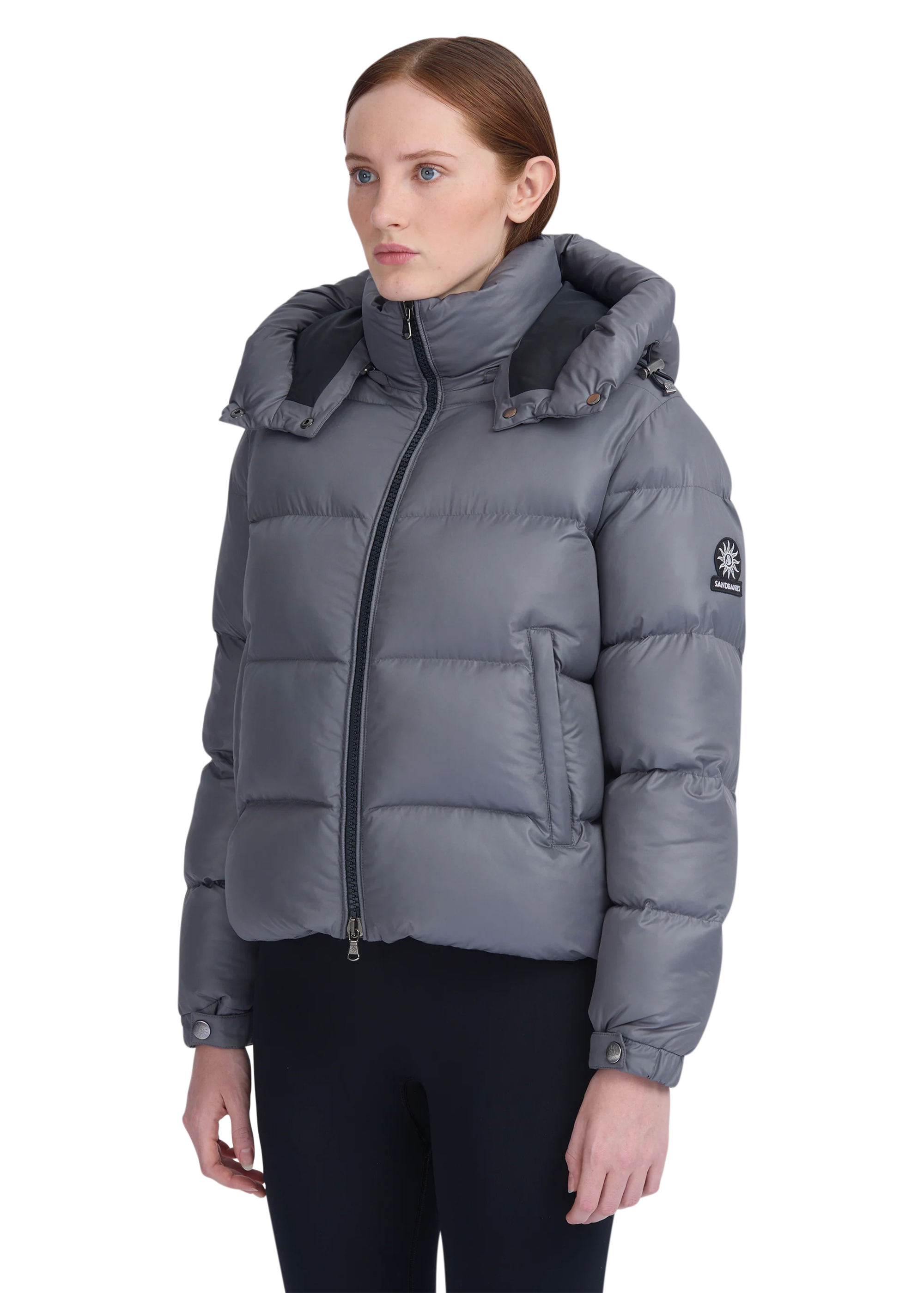 Woman wearing a gray puffer jacket on a white background
