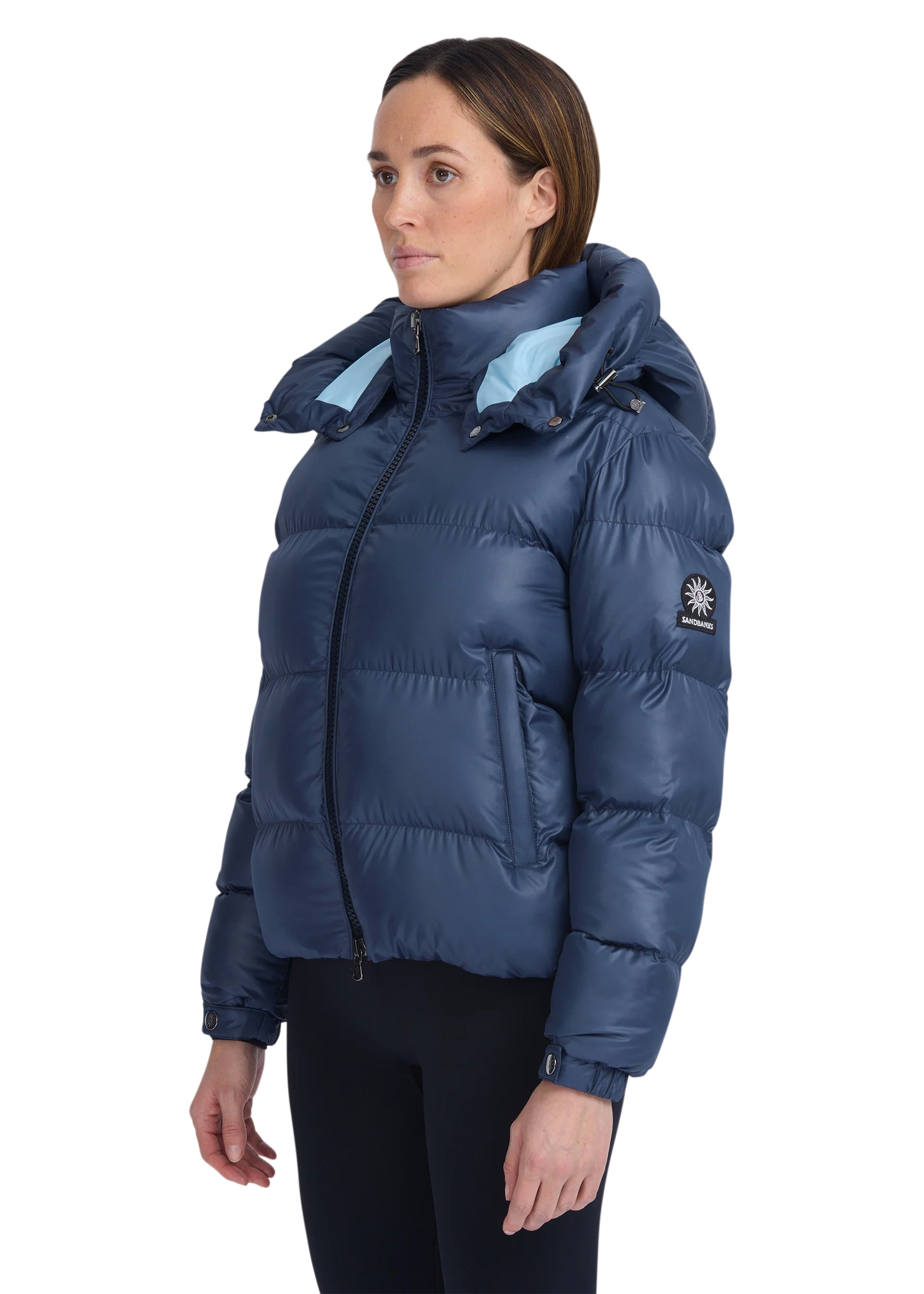 Woman wearing a blue puffer jacket with a brand logo on a white background