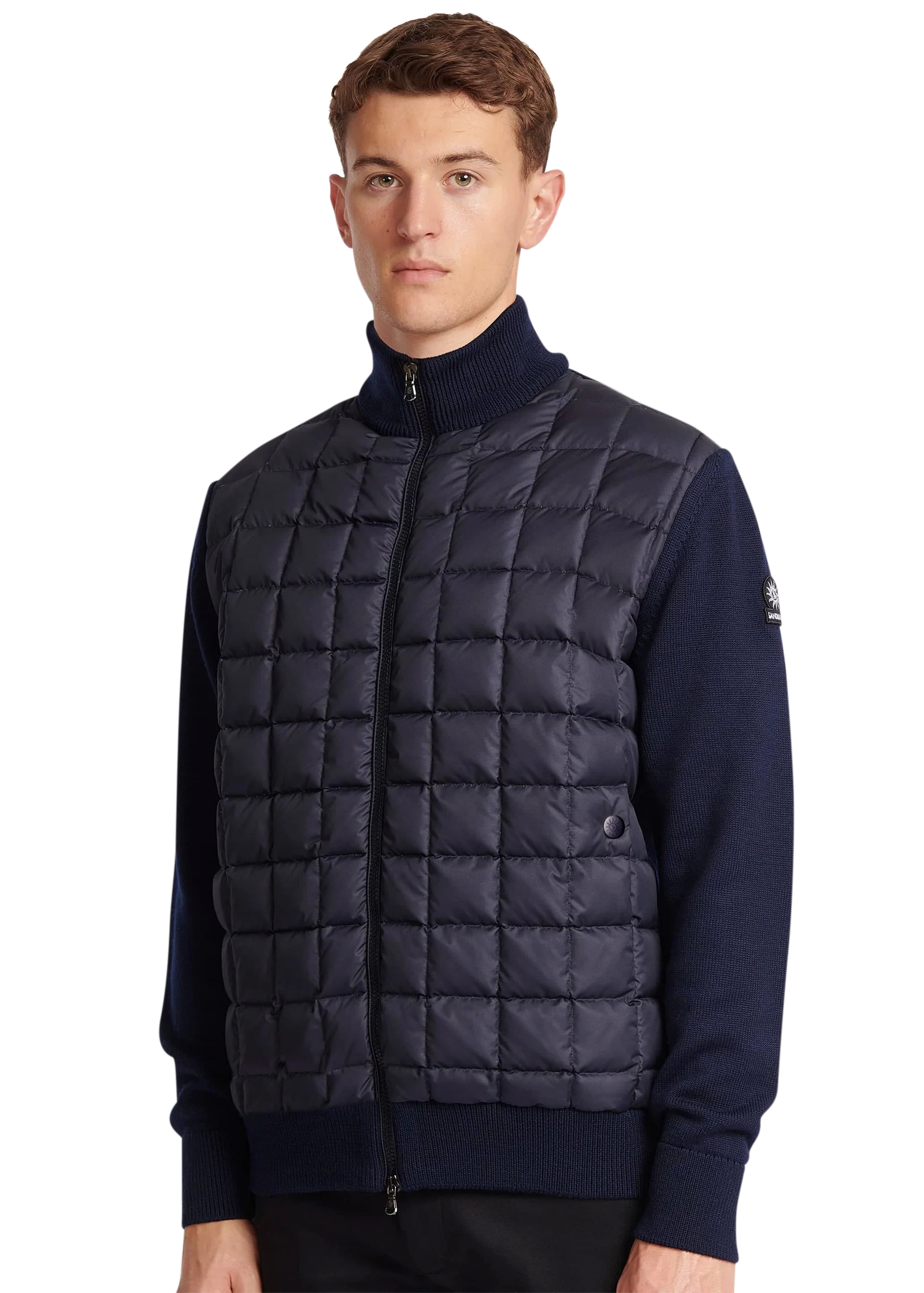 Man wearing a navy puffer vest over a dark sweater on a white background