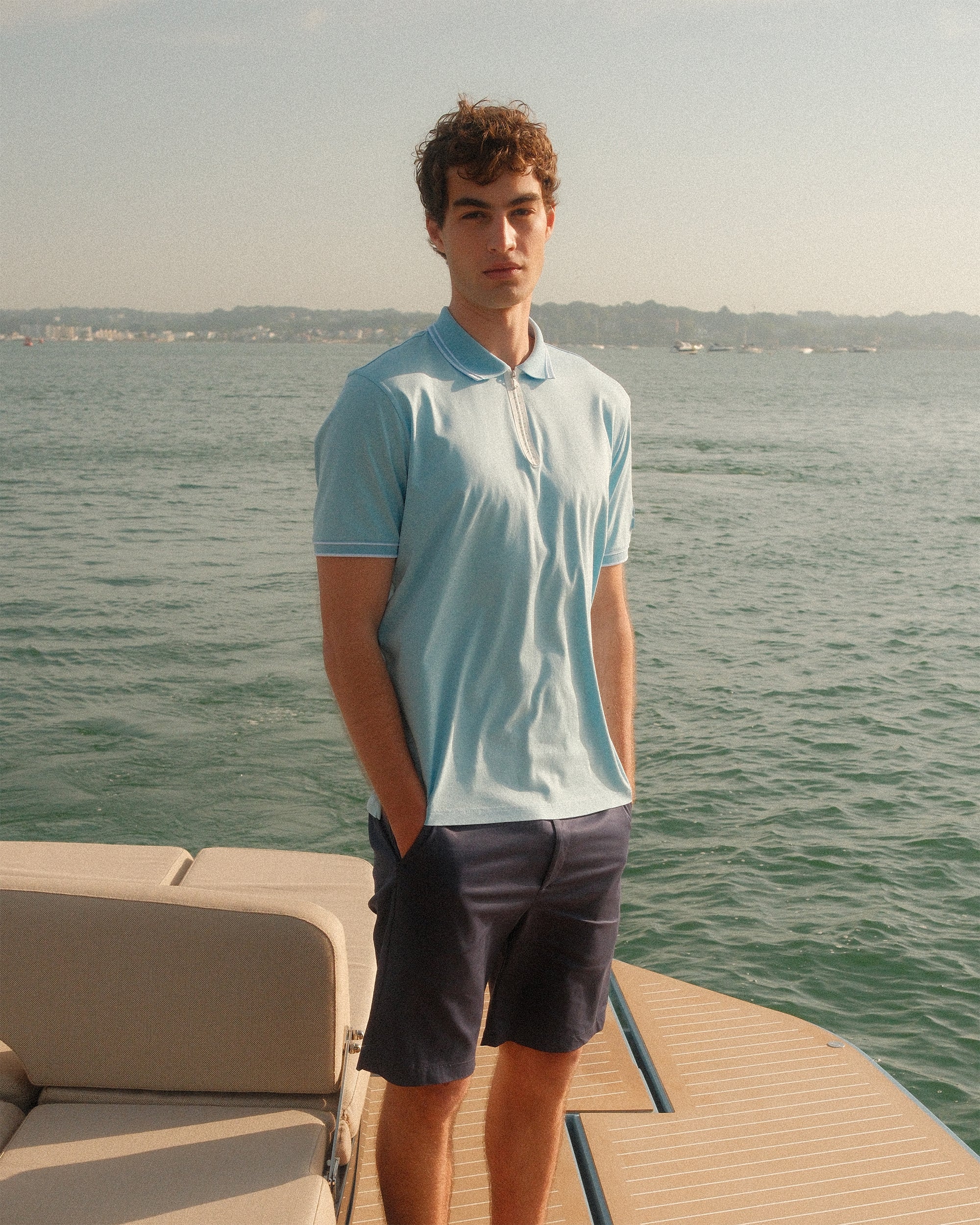 Man standing on a boat deck with water and sky in the background
