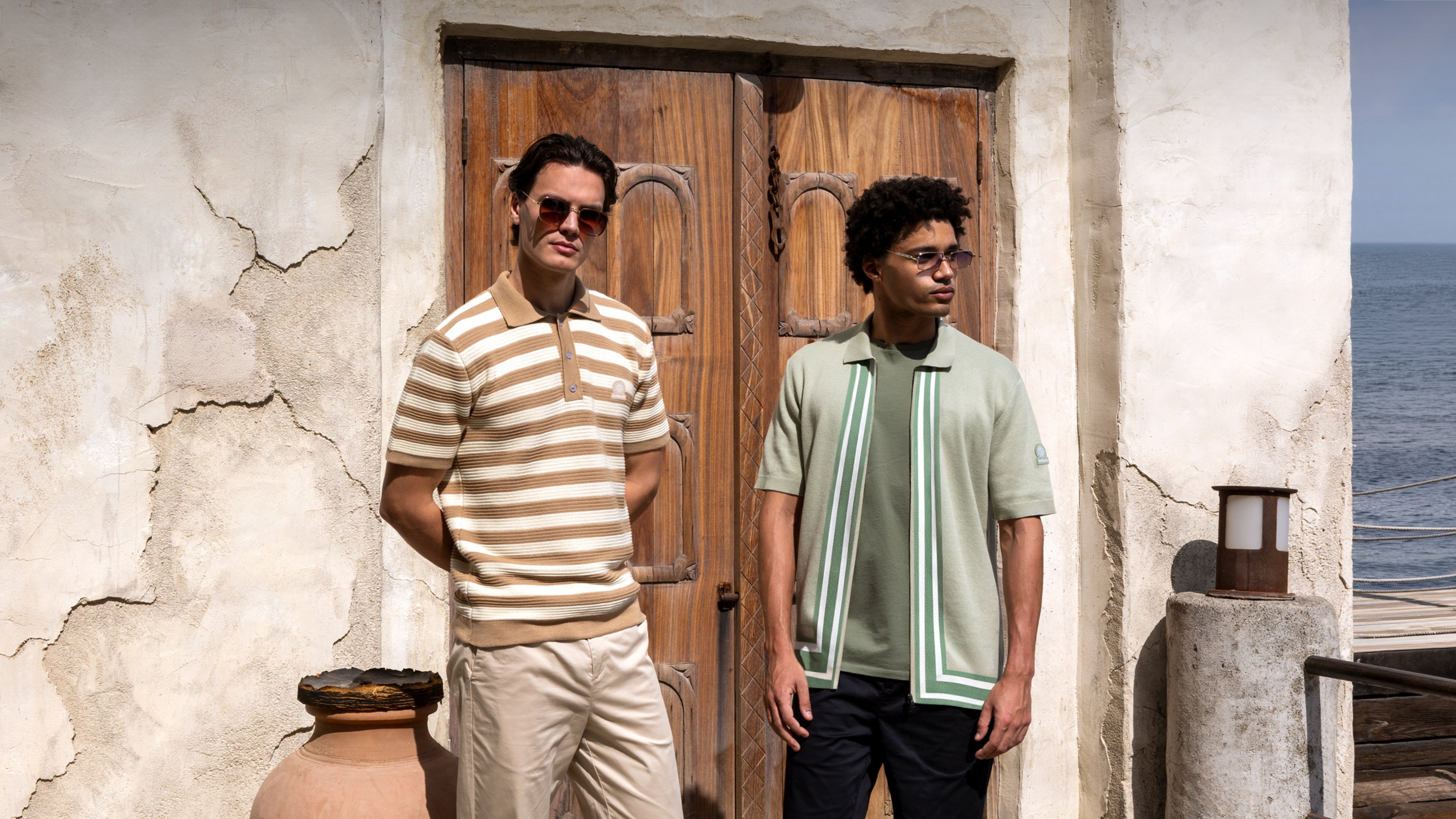 Two men standing in front of a wooden door with ocean view