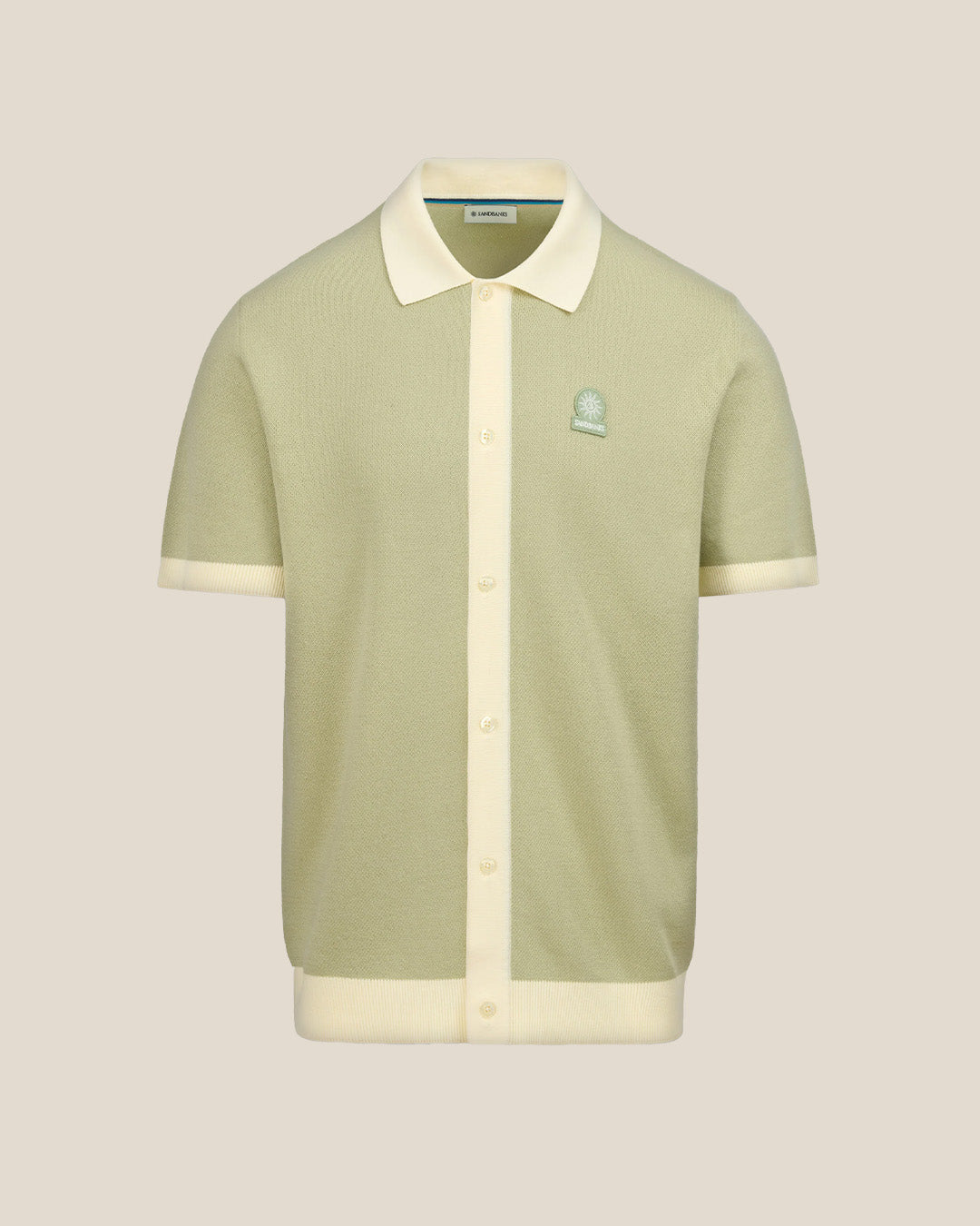 Light green polo shirt with white collar and trim on a beige background