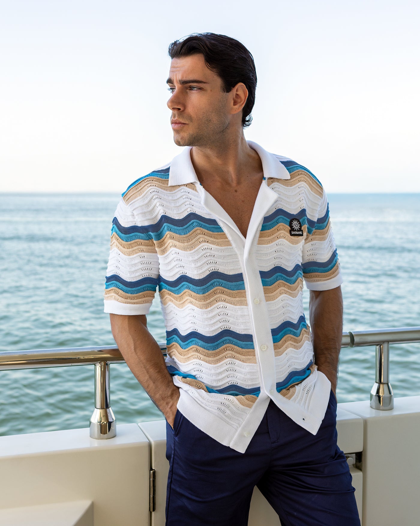 Man wearing a striped shirt with a blurred ocean background