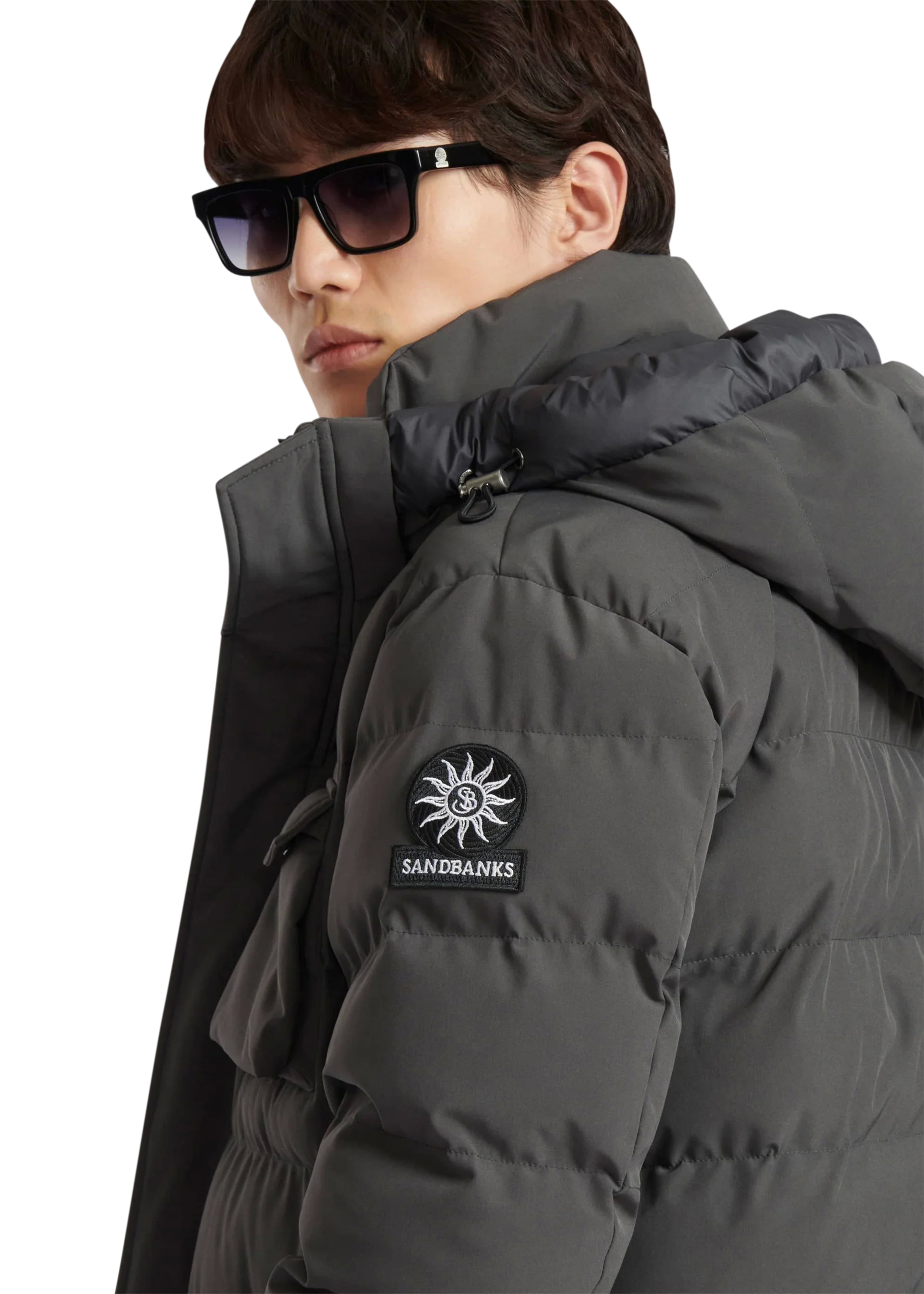 Person wearing a dark gray puffer jacket with a brand logo on a white background