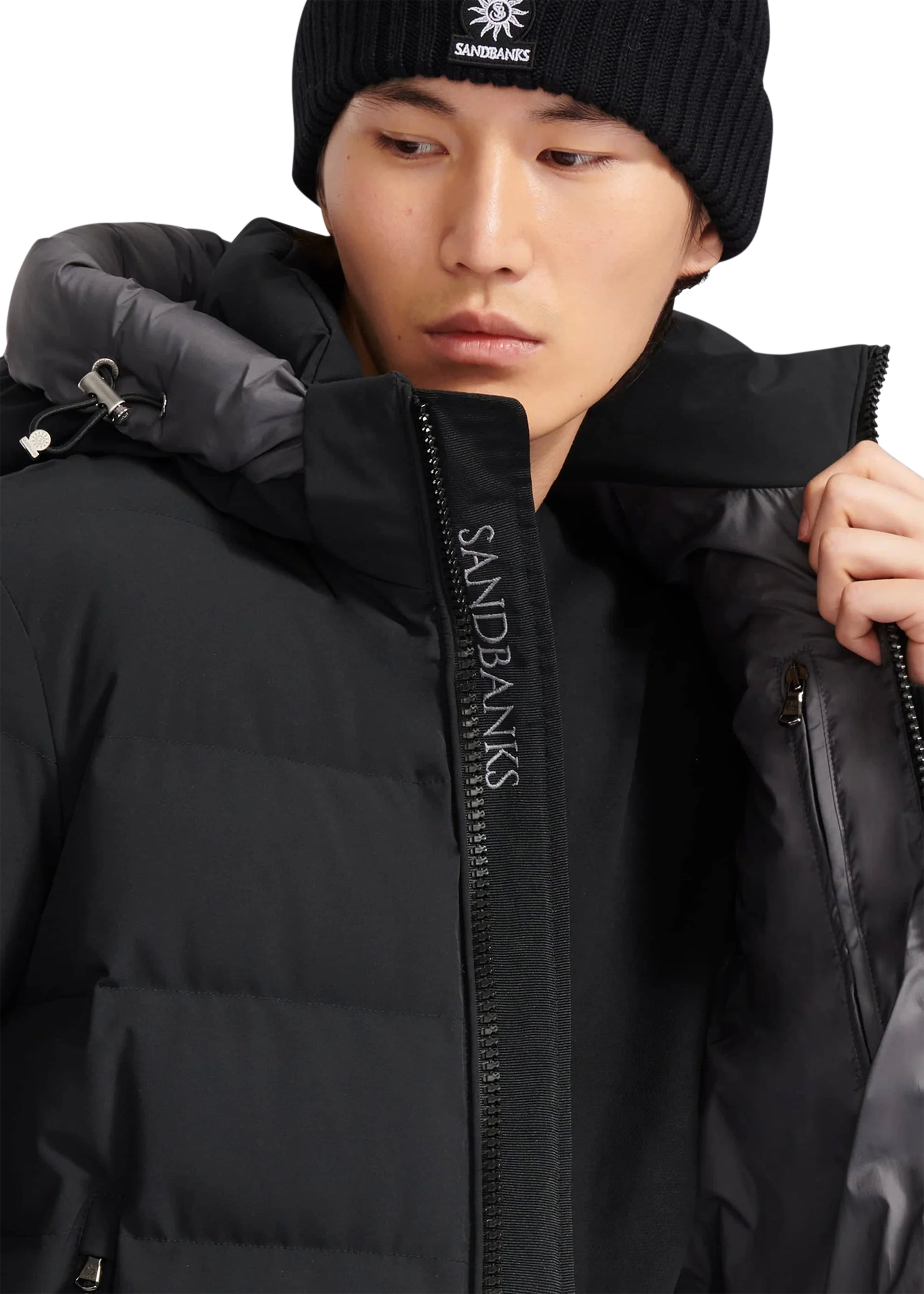Person wearing a black puffer jacket with 'Sandbanks' branding.