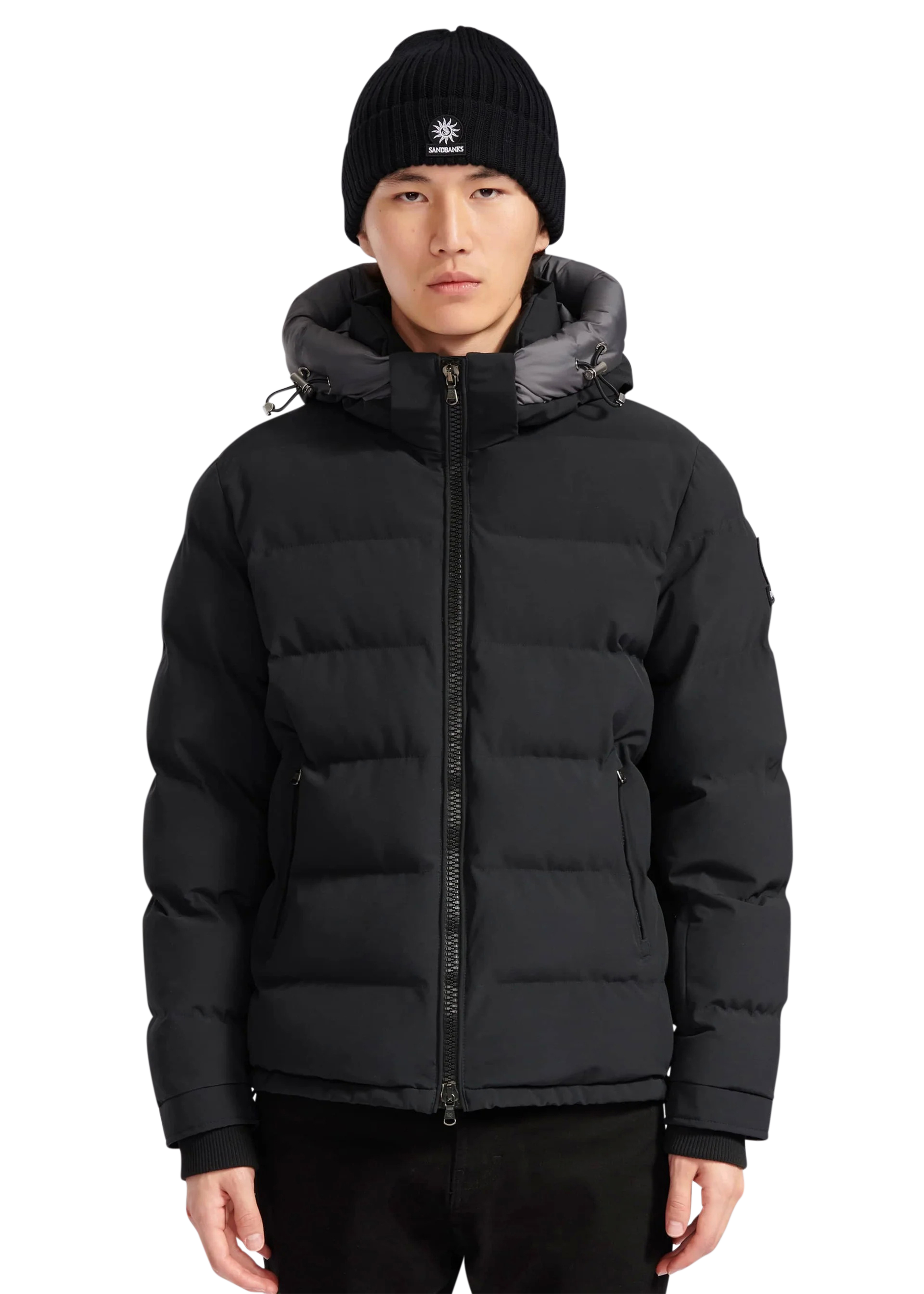 Person wearing a black puffer jacket and matching beanie on a white background