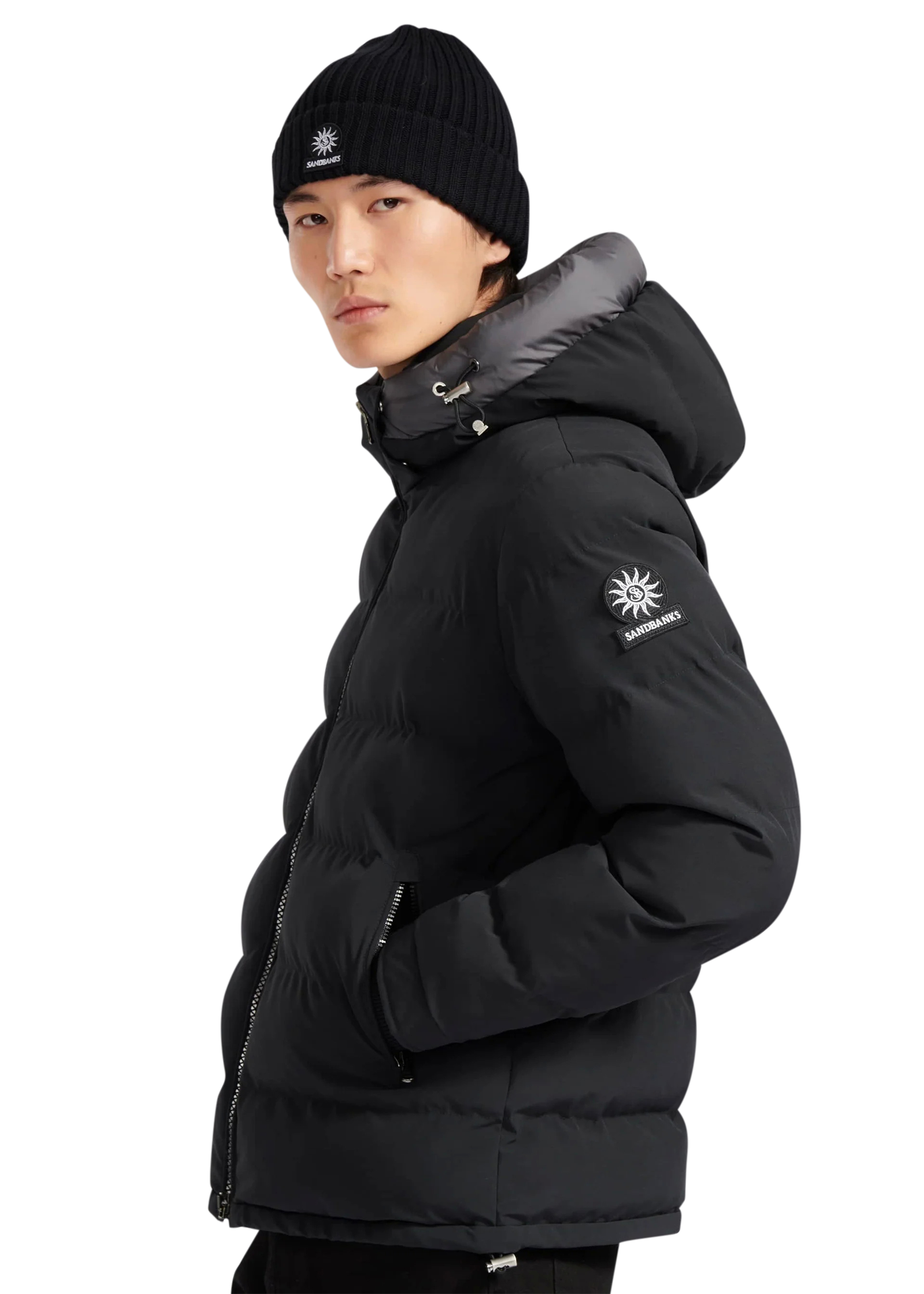 Person wearing a black puffer jacket with a brand logo on a white background