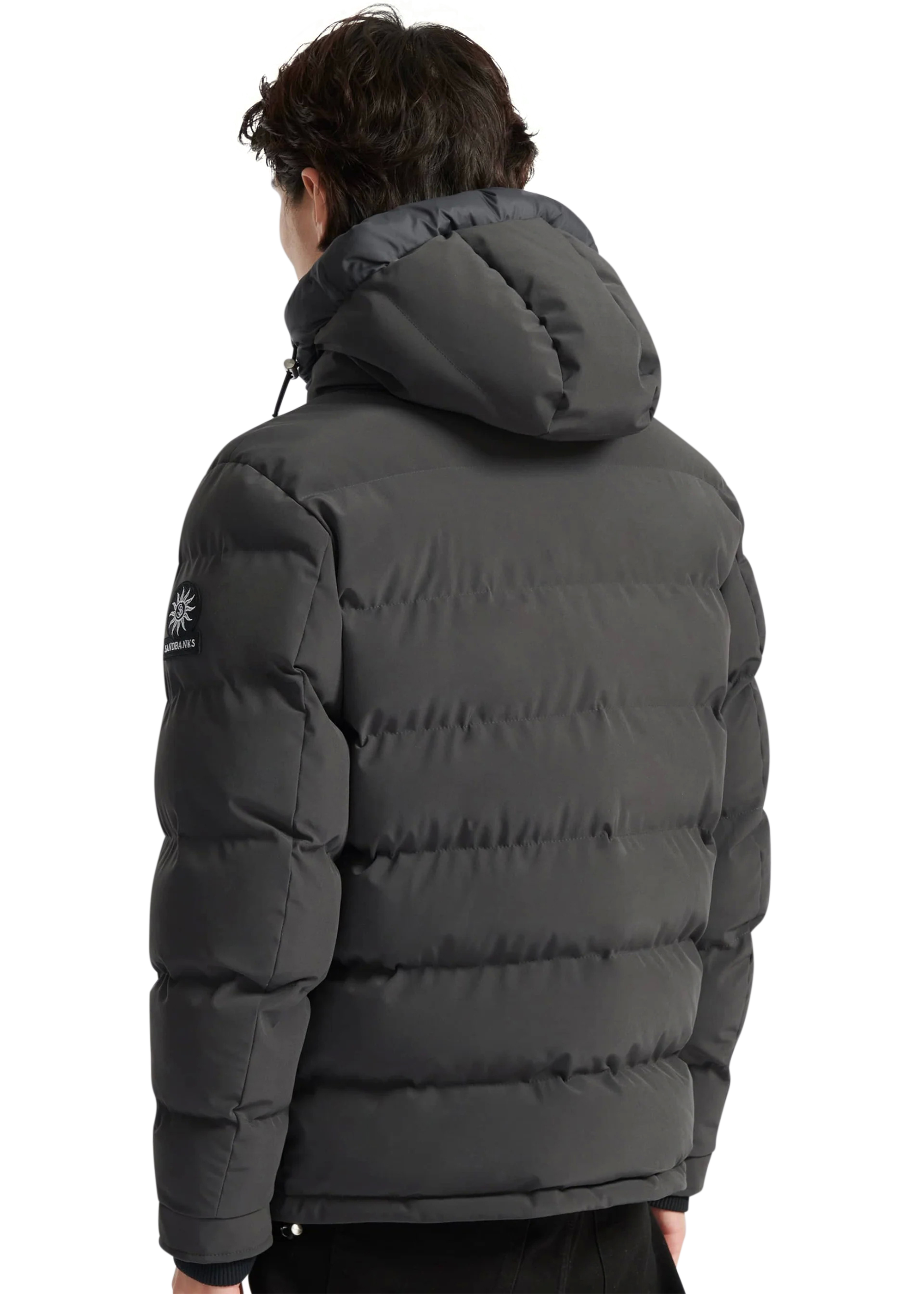 Person wearing a dark gray puffer jacket with a brand logo on the back, standing against a white background.