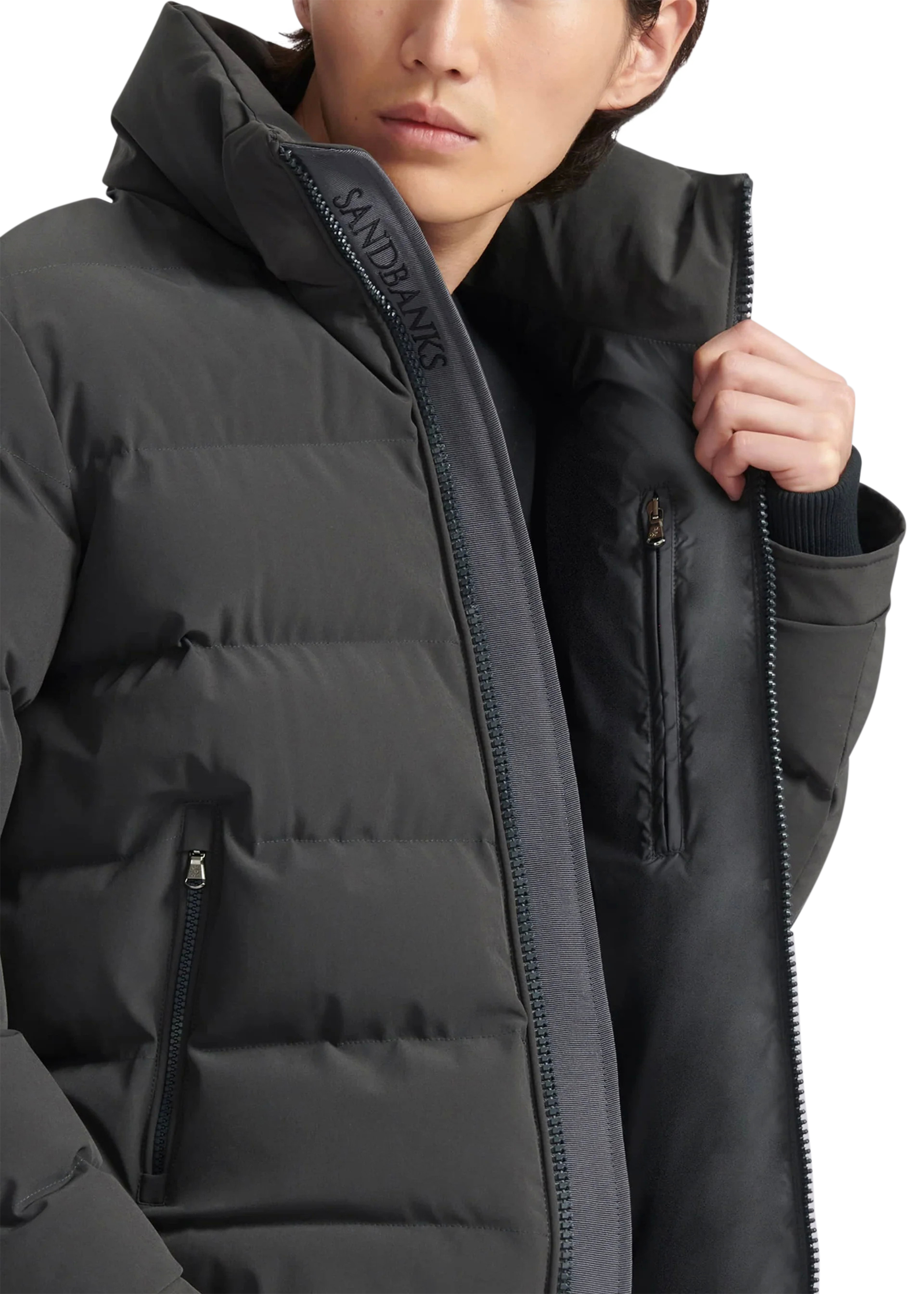 Person wearing a black winter coat with a brand logo on a white background