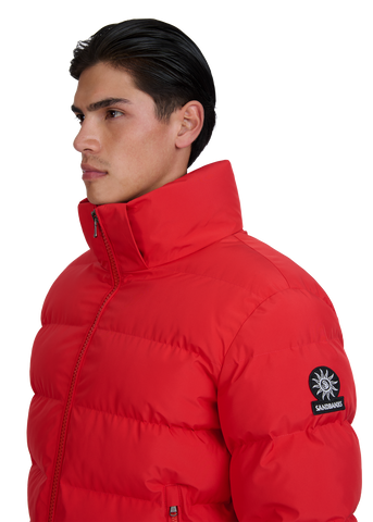 Man wearing a red puffer jacket with a brand logo on a white background