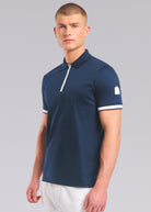 Model wearing a navy polo shirt with white accents on a gray background