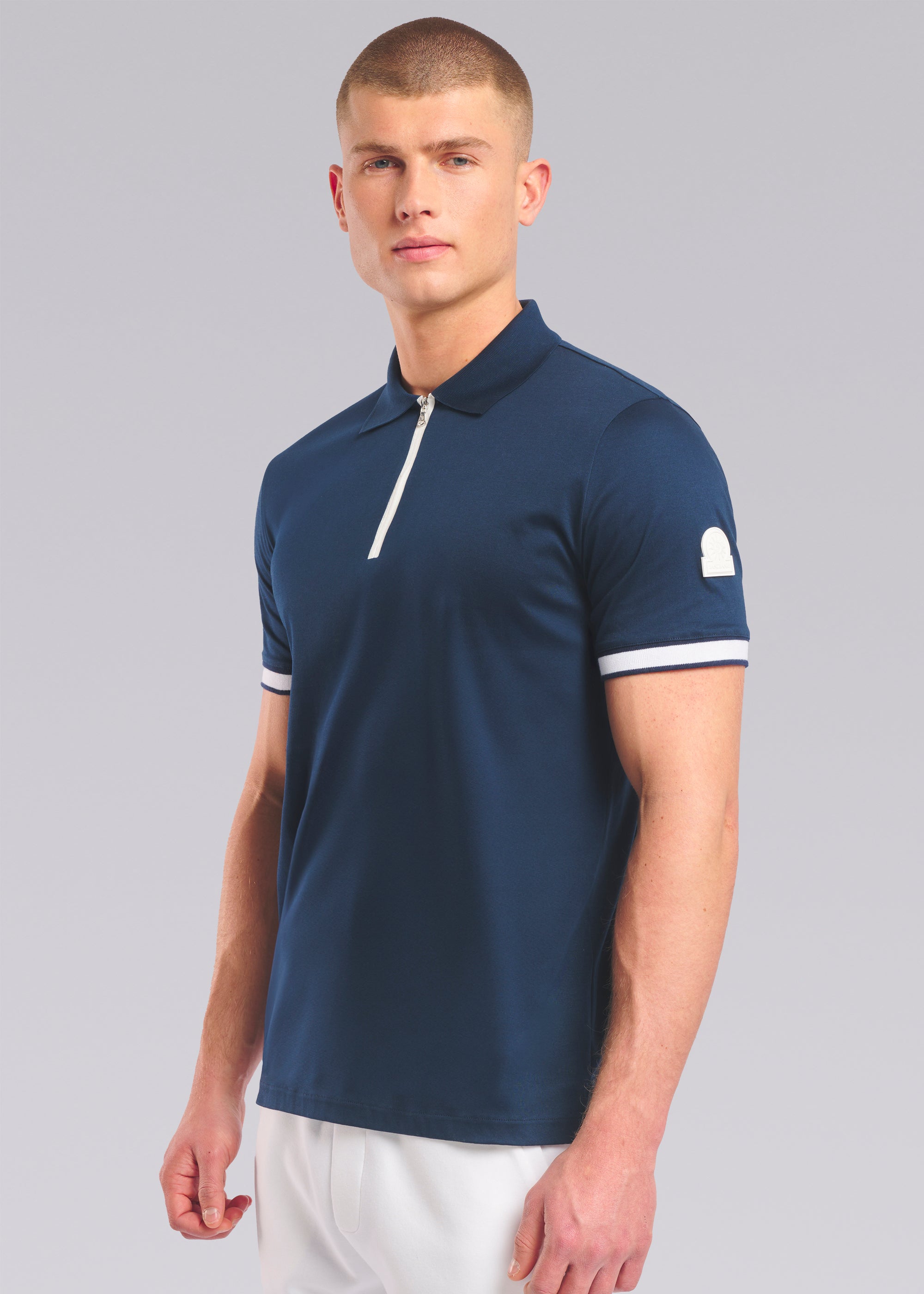 Model wearing a navy polo shirt with white accents on a gray background