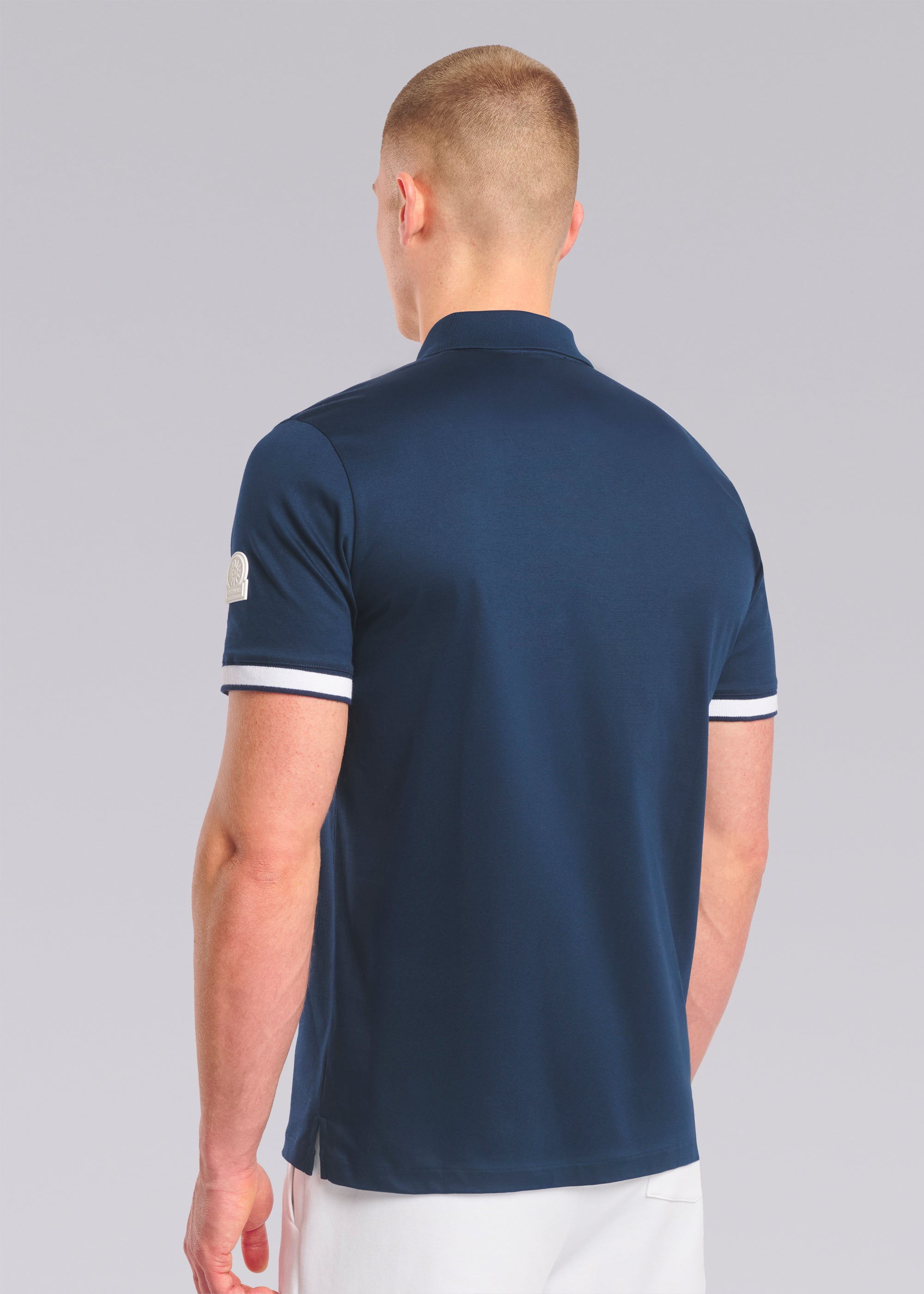 Model wearing a navy polo shirt with white trim on a gray background