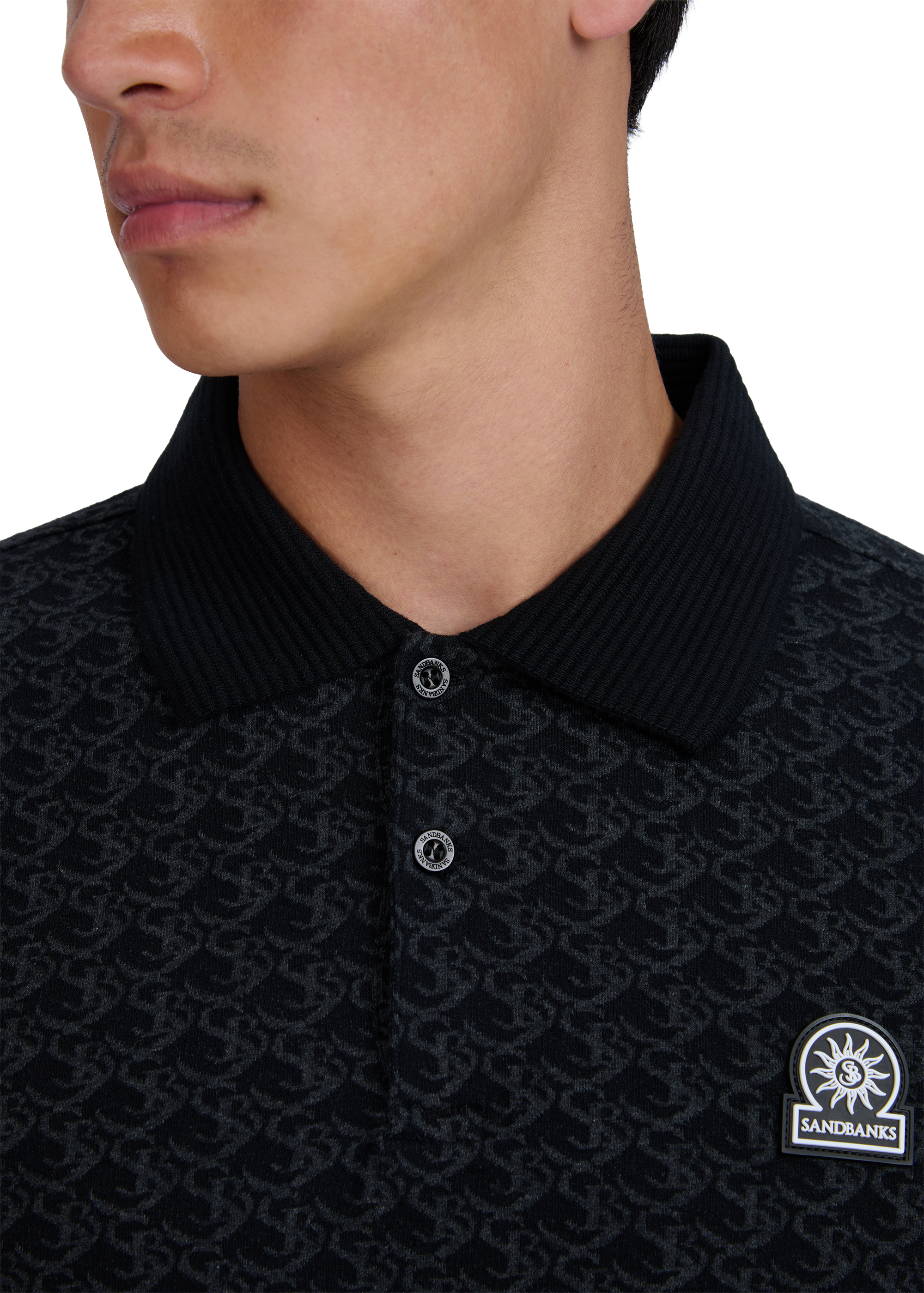 Close-up of a model wearing a black patterned polo shirt with a brand logo on a white background