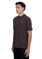 Model wearing a brown t-shirt with a logo on a white background
