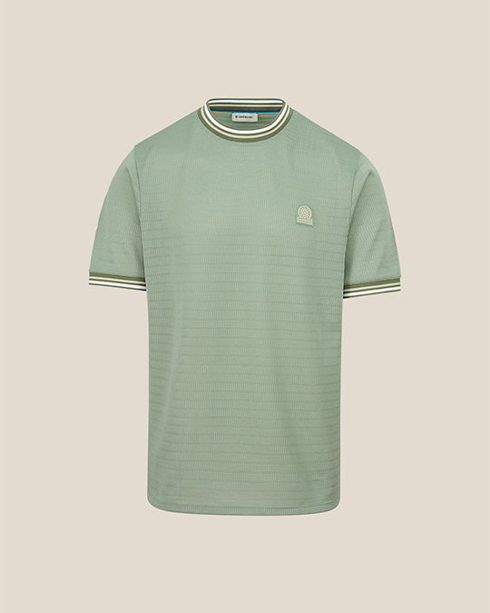 Green ribbed t-shirt with a small logo on a beige background
