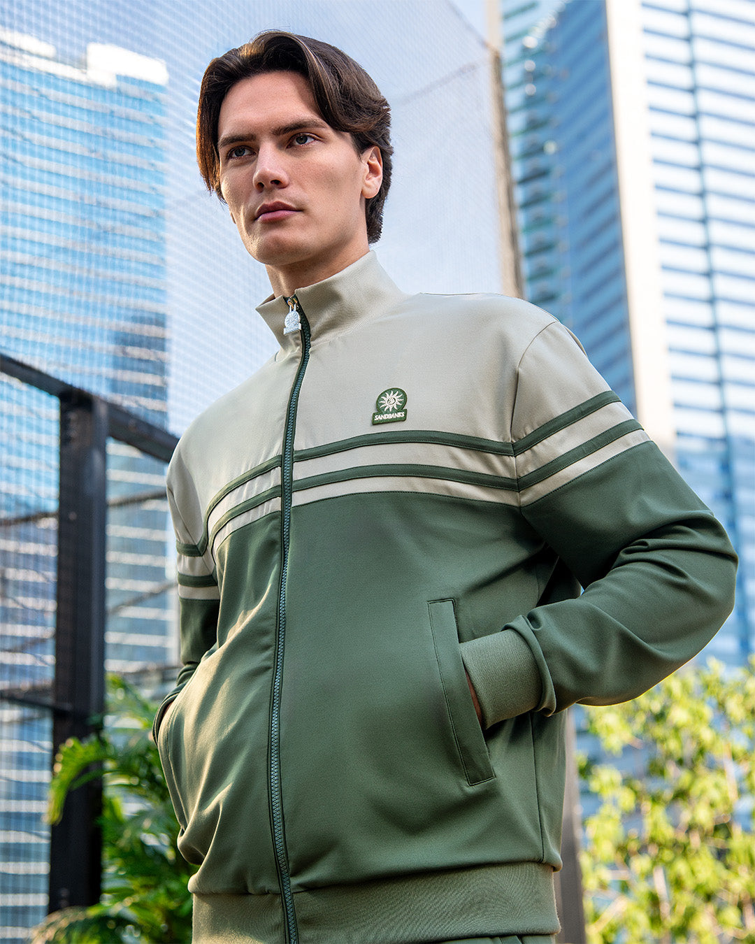 Man wearing a green tracksuit with a logo in an urban setting