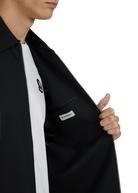 Person wearing a black jacket with a visible brand logo on a white background