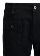 Close-up of black pants with a pocket and button details on a white background