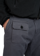 Close-up of gray pants with a pocket and button, worn with a black jacket.