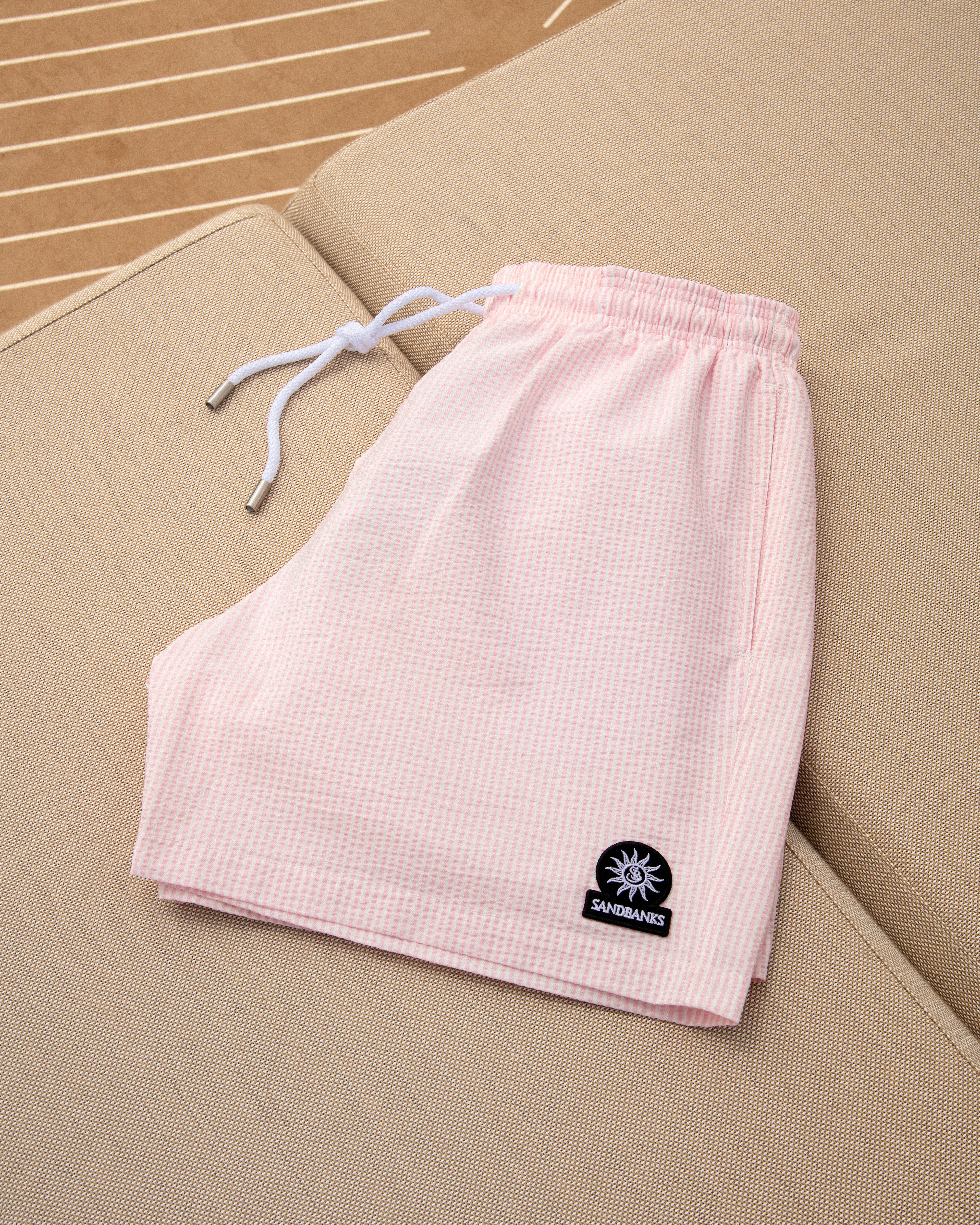 Pink checkered shorts with a logo on a beige surface