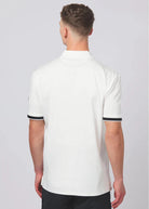 Man wearing a white polo shirt with black trim on a plain background