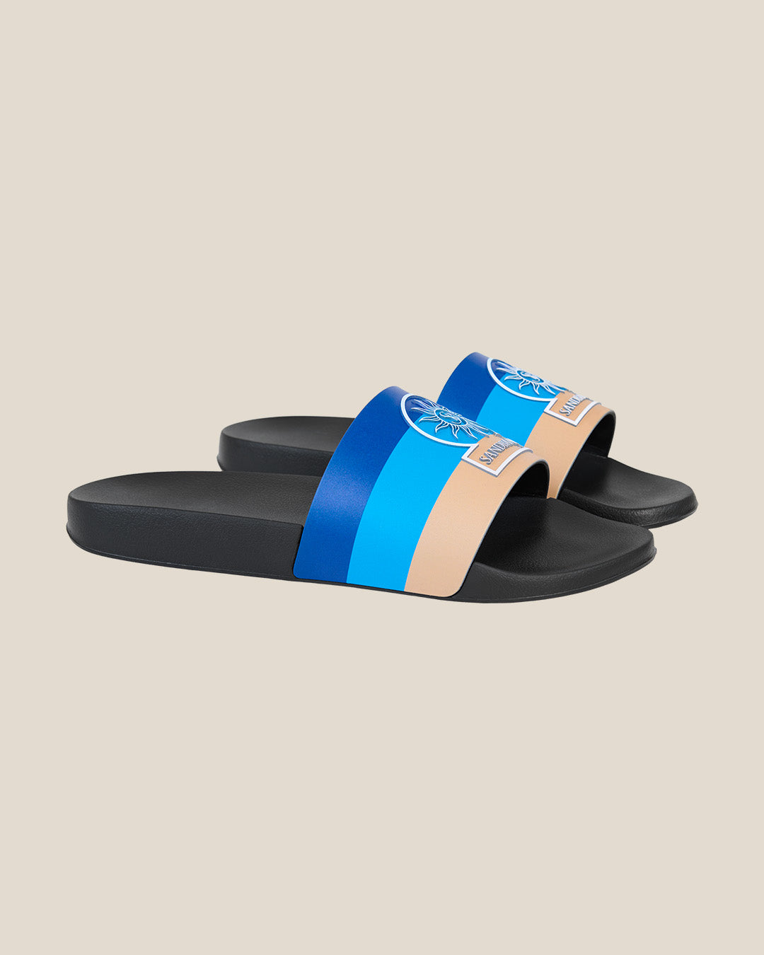 Black slide sandals with blue and beige straps on a beige background