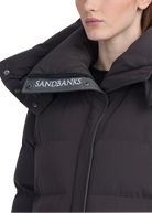 Close-up of a black puffer jacket with 'Sandbanks' branding on a white background