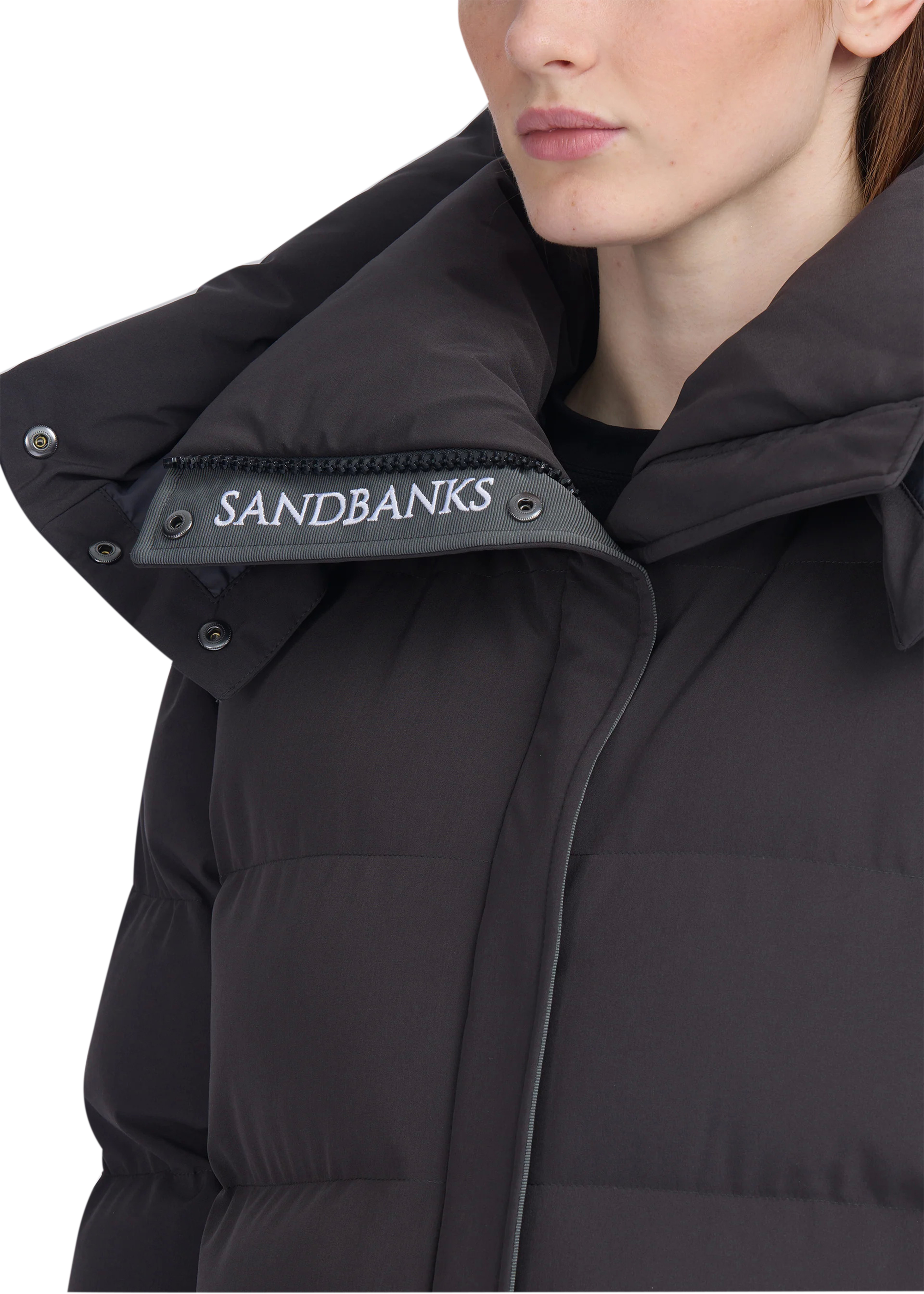 Close-up of a black puffer jacket with 'Sandbanks' branding on a white background