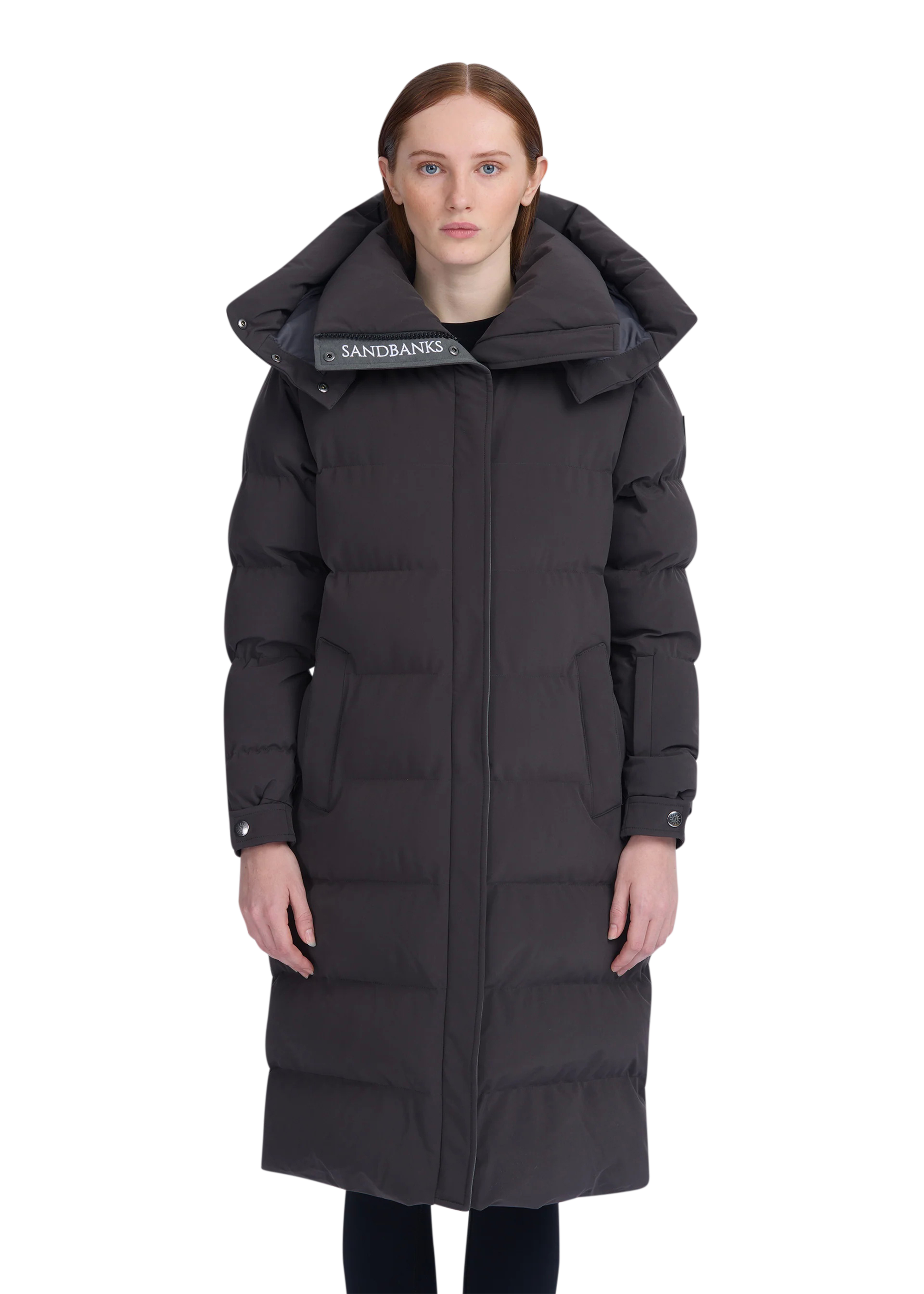 Woman wearing a black winter coat with a hood on a white background