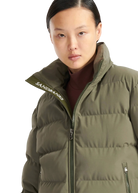 Person wearing a green puffer jacket with 'Sandbanks' branding on a white background
