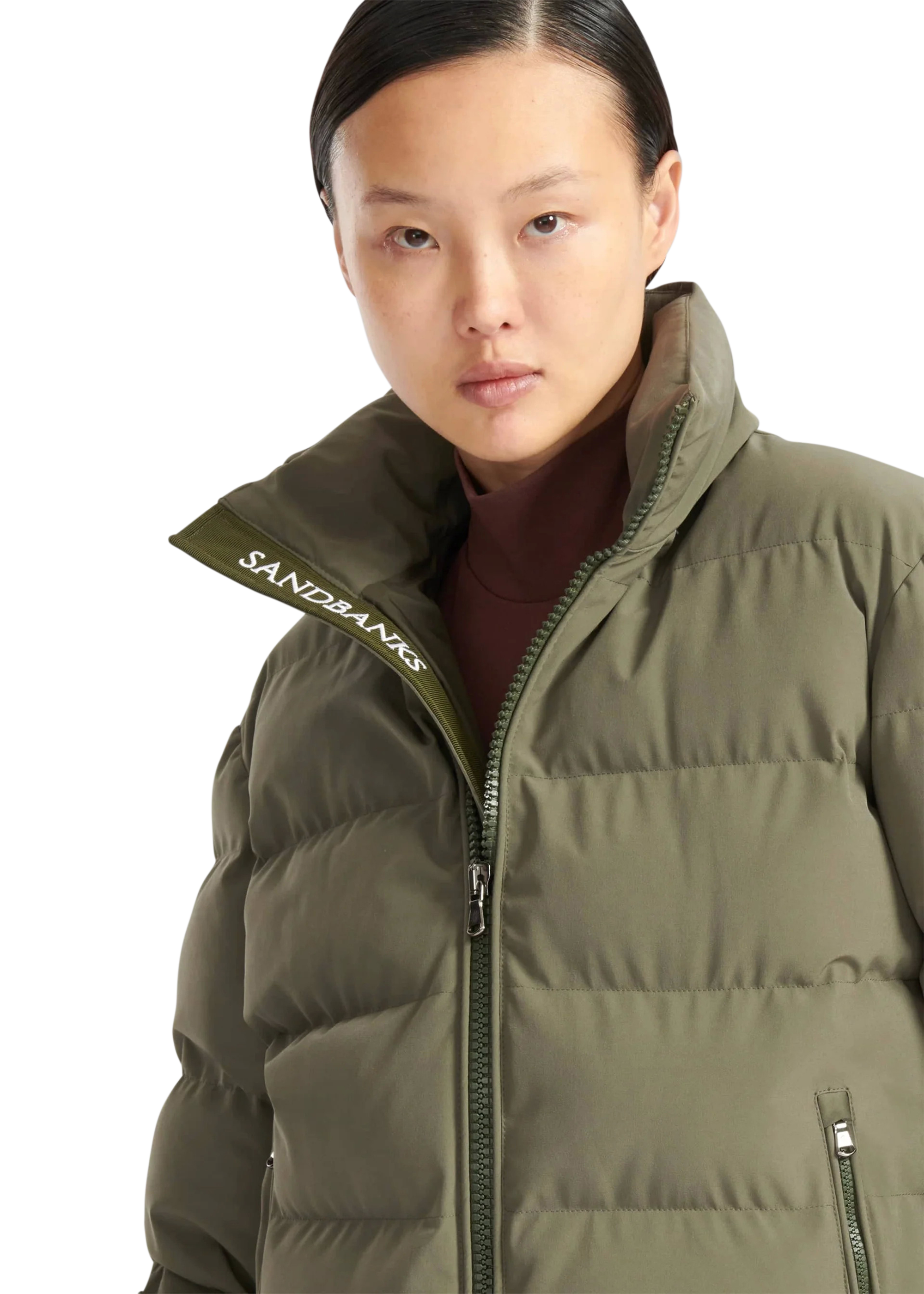 Person wearing a green puffer jacket with 'Sandbanks' branding on a white background